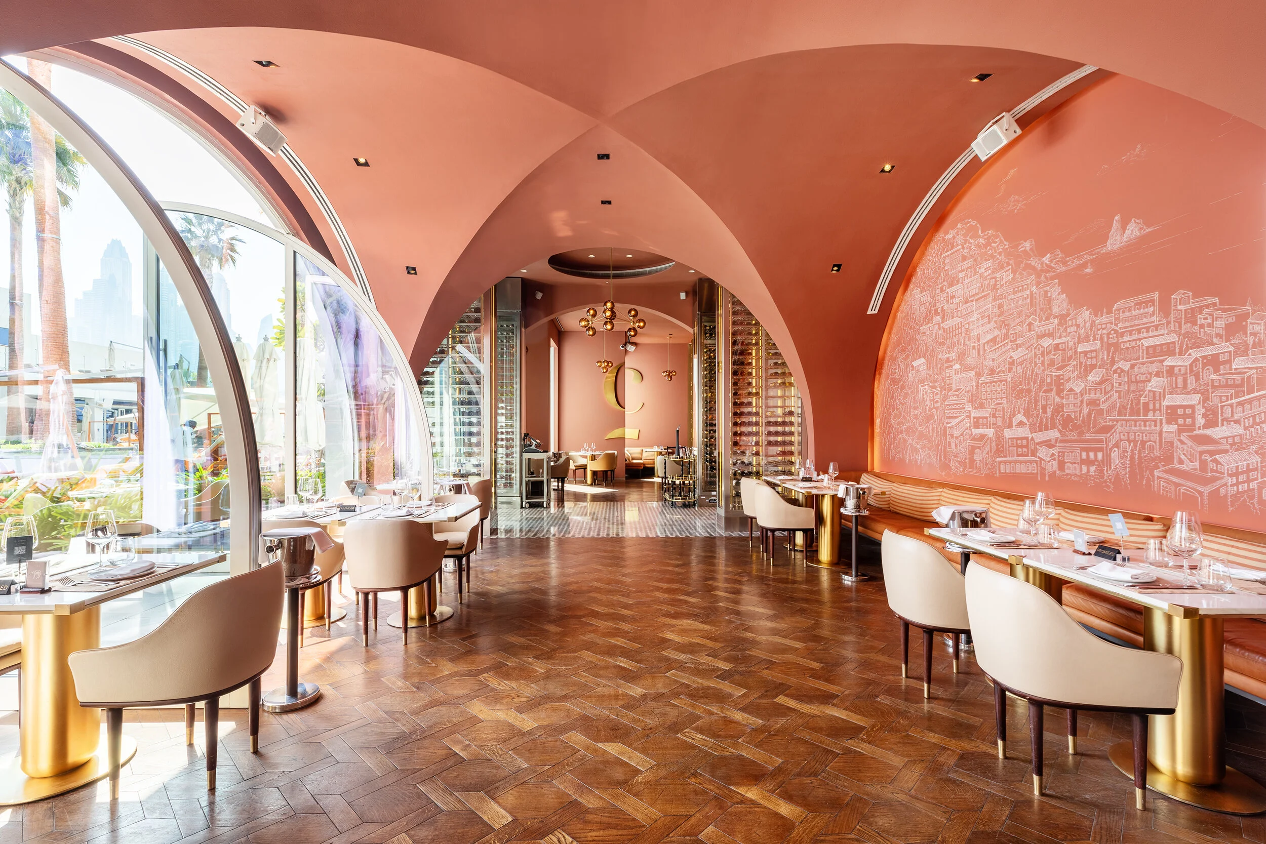 Luxury restaurant interior with curved architecture, elegant tables, cushioned chairs, large arched windows, wine racks, and decorative wall drawings.
