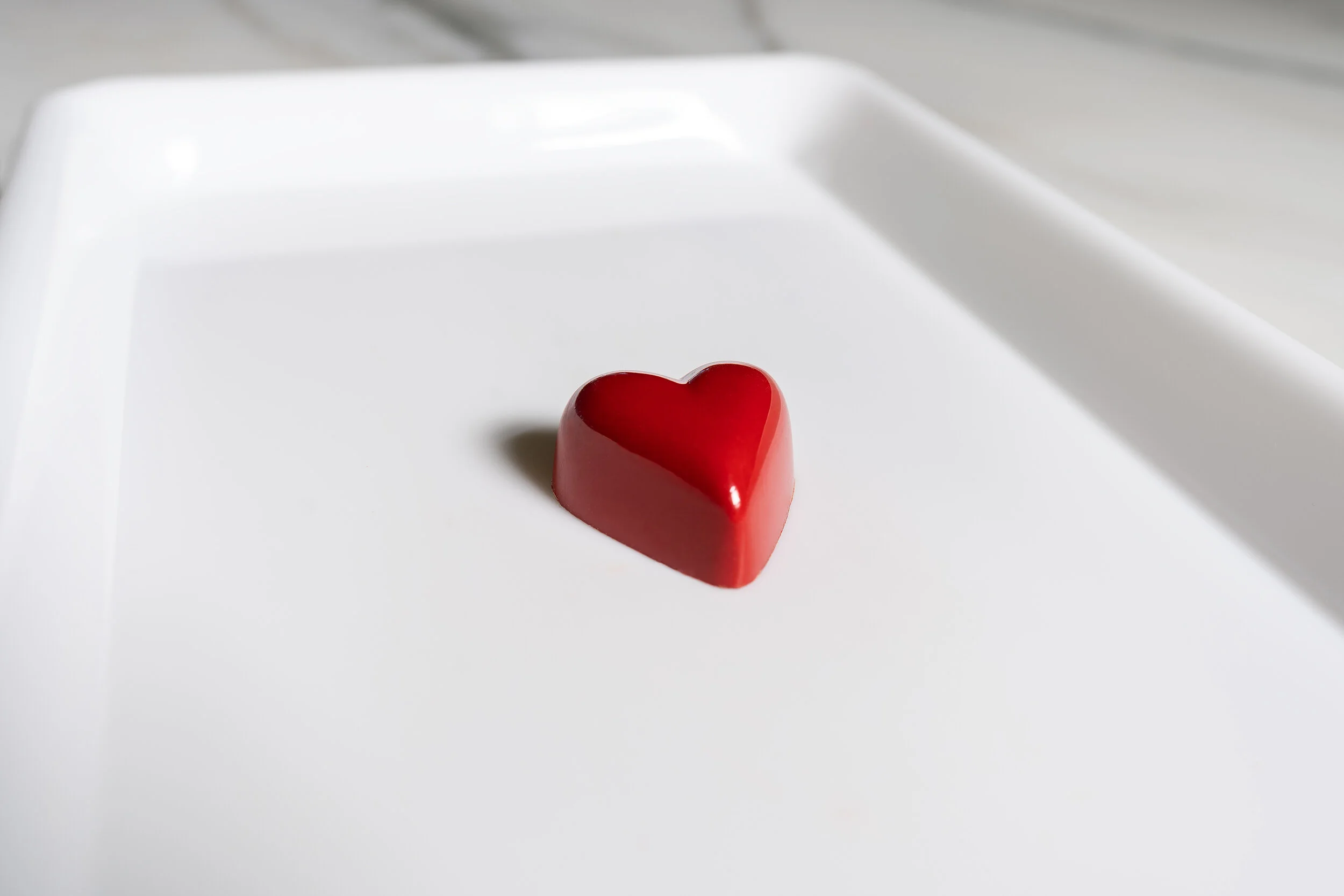 Red heart-shaped chocolate on a white plate