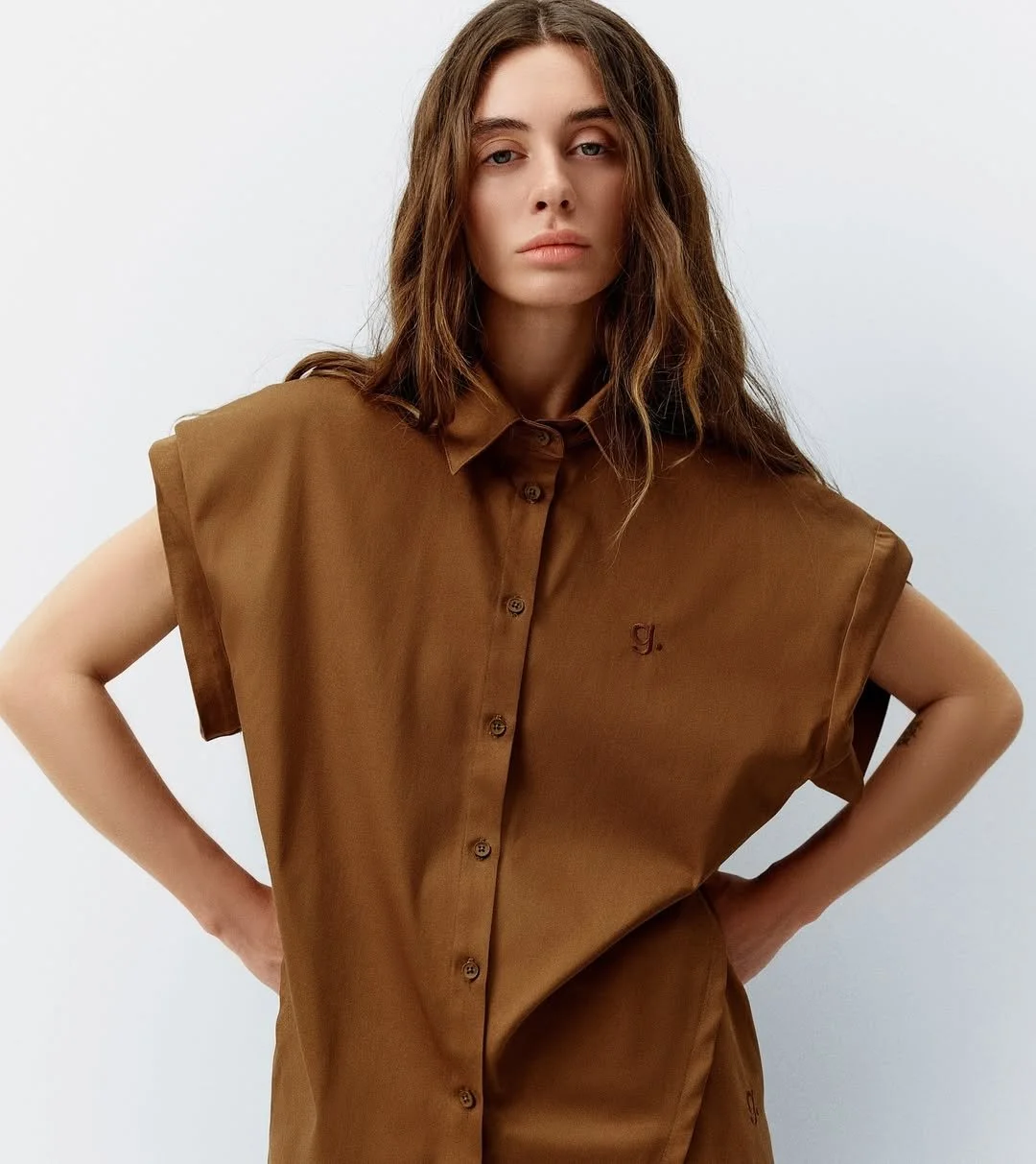 Person wearing a short-sleeved brown button-up shirt.