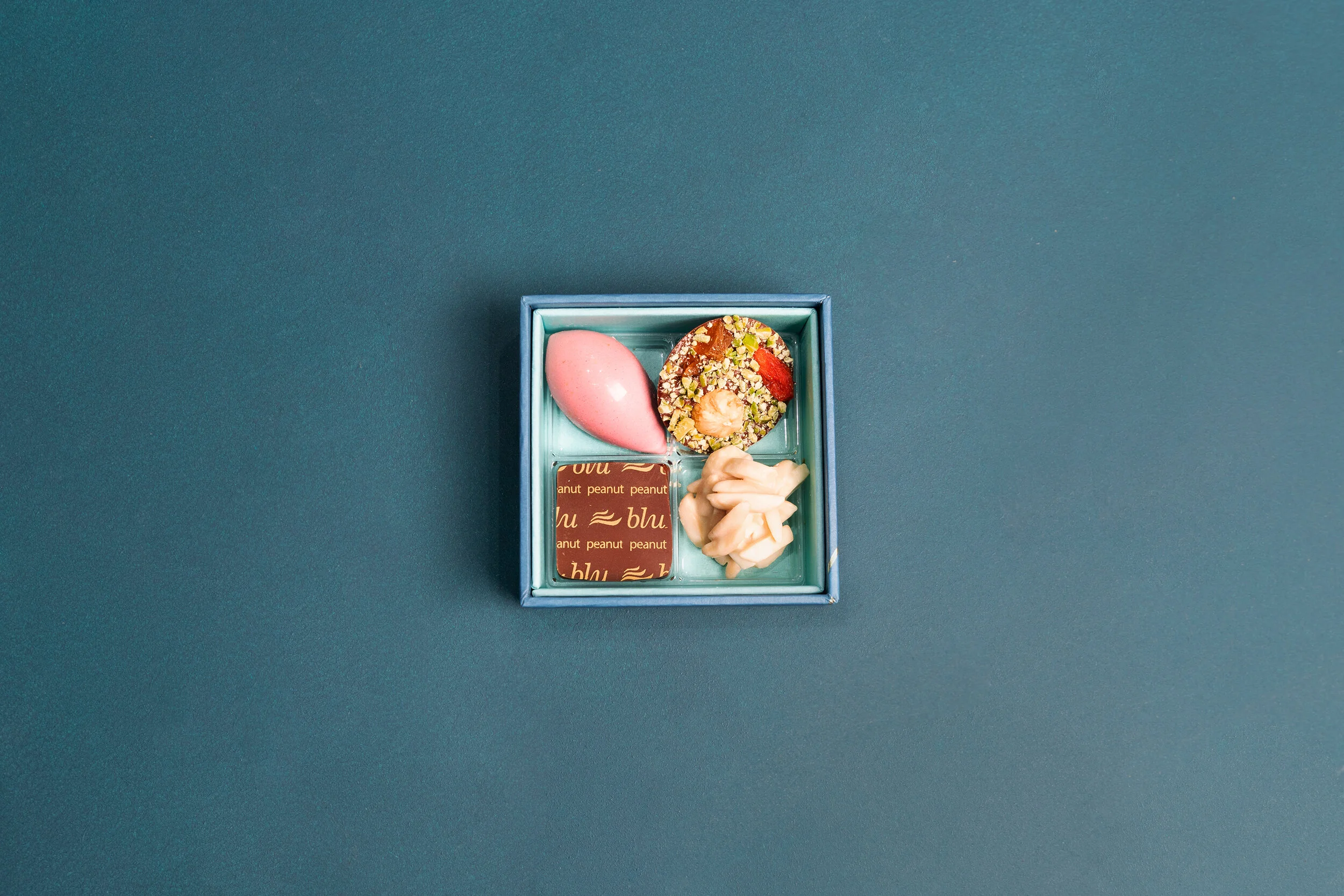 Assorted chocolates in a blue box on a blue background.