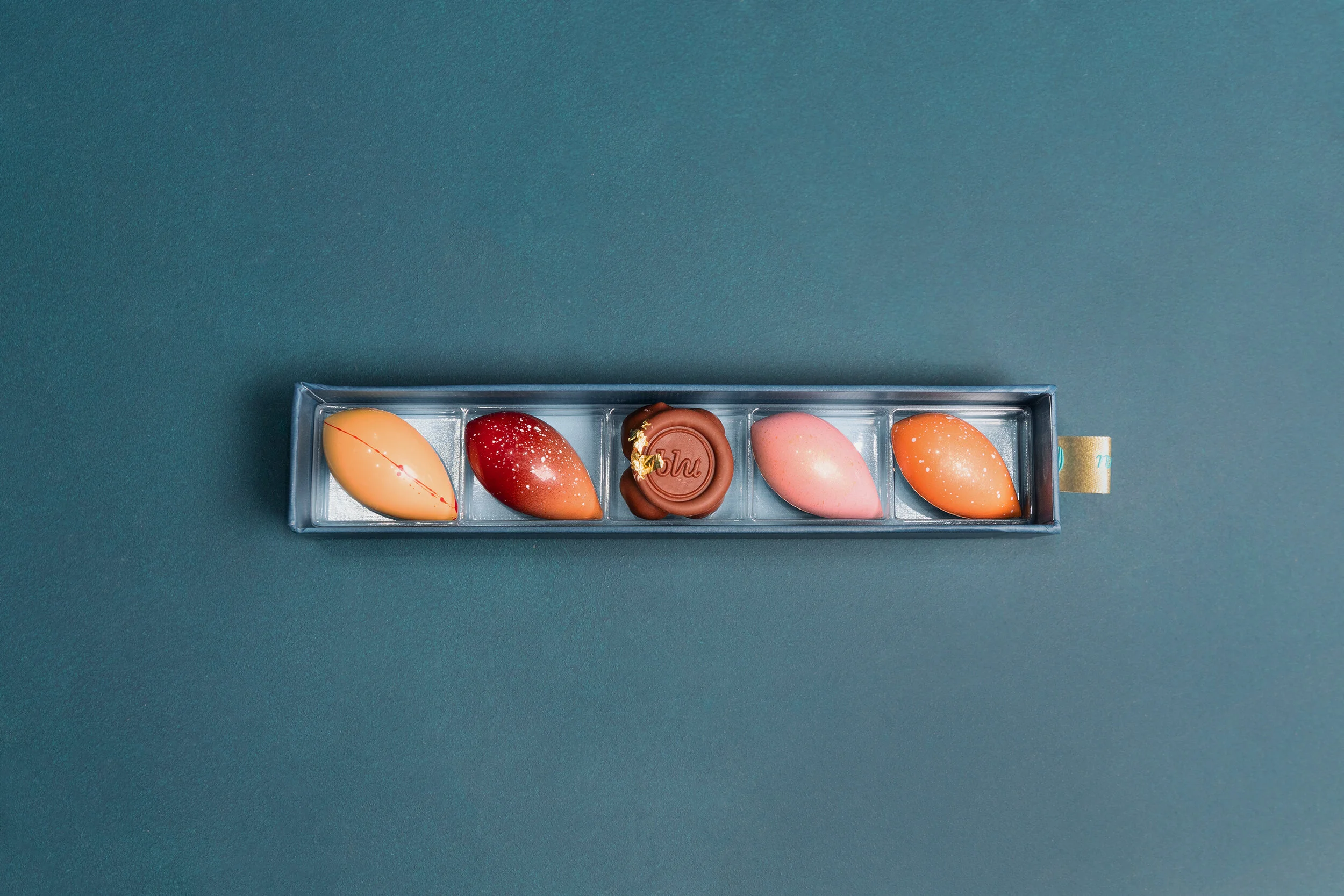 Elegantly crafted chocolates in a rectangular box with teal background