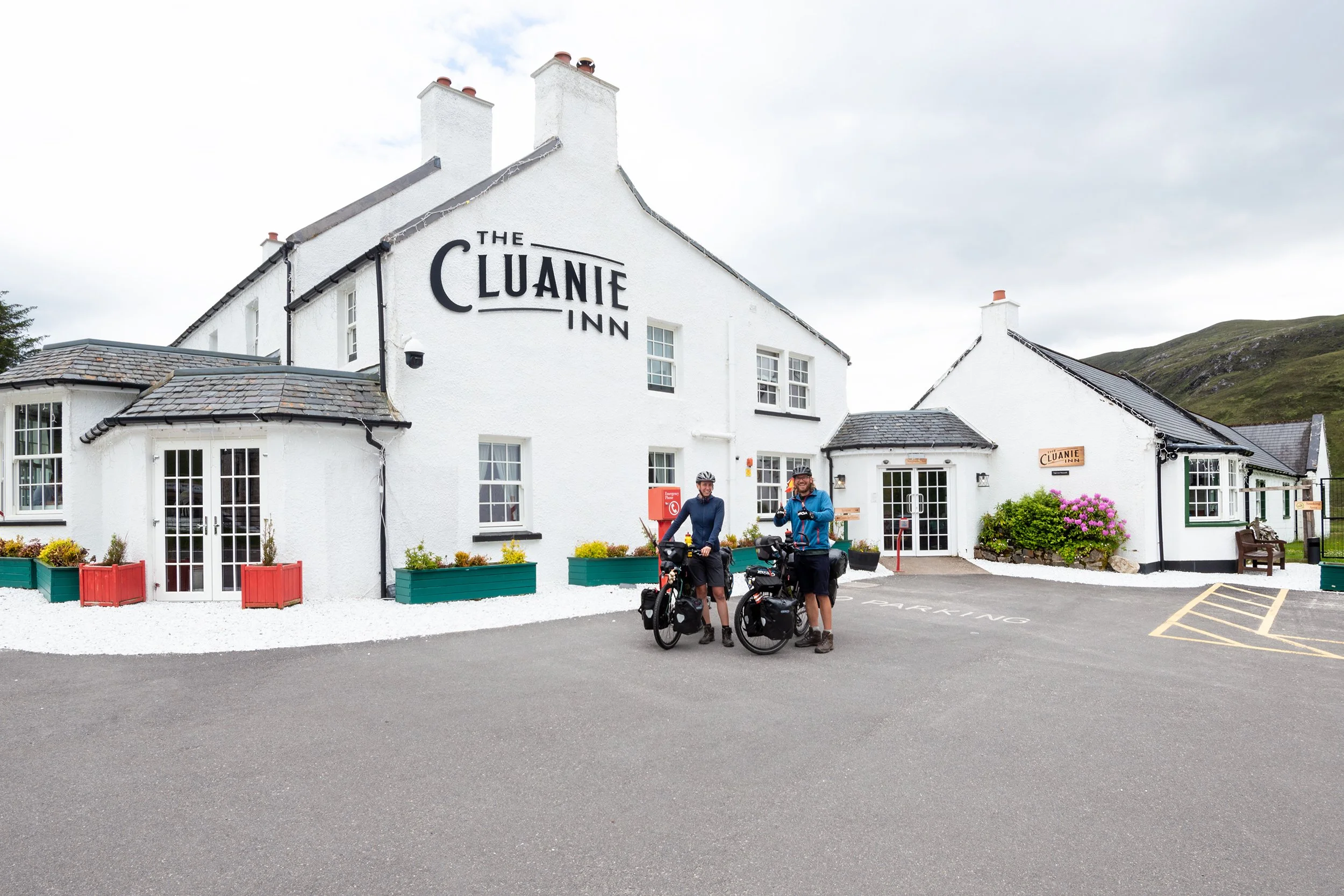 The Cluanie Inn building with two cyclists in front.