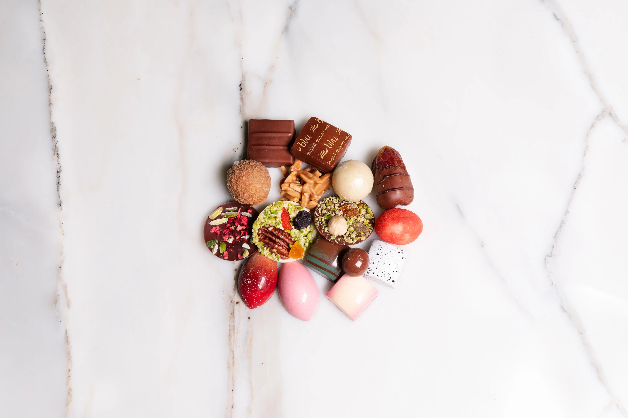 Assorted artisan chocolates arranged on a white marble surface.