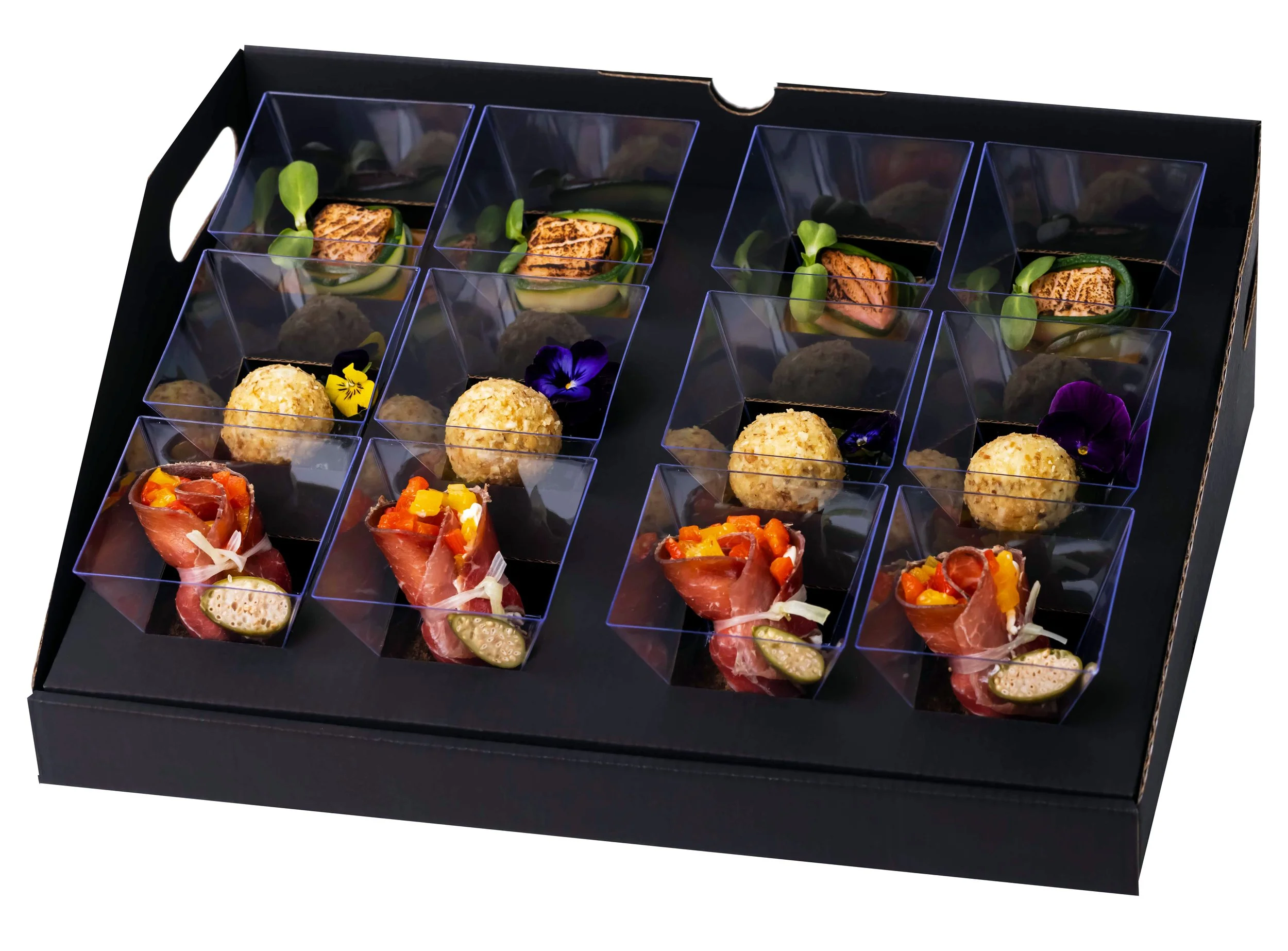 Assorted gourmet appetizers arranged in a tray with plastic compartments, featuring rolls of meat with vegetables, cheese balls, and decorated with edible flowers.