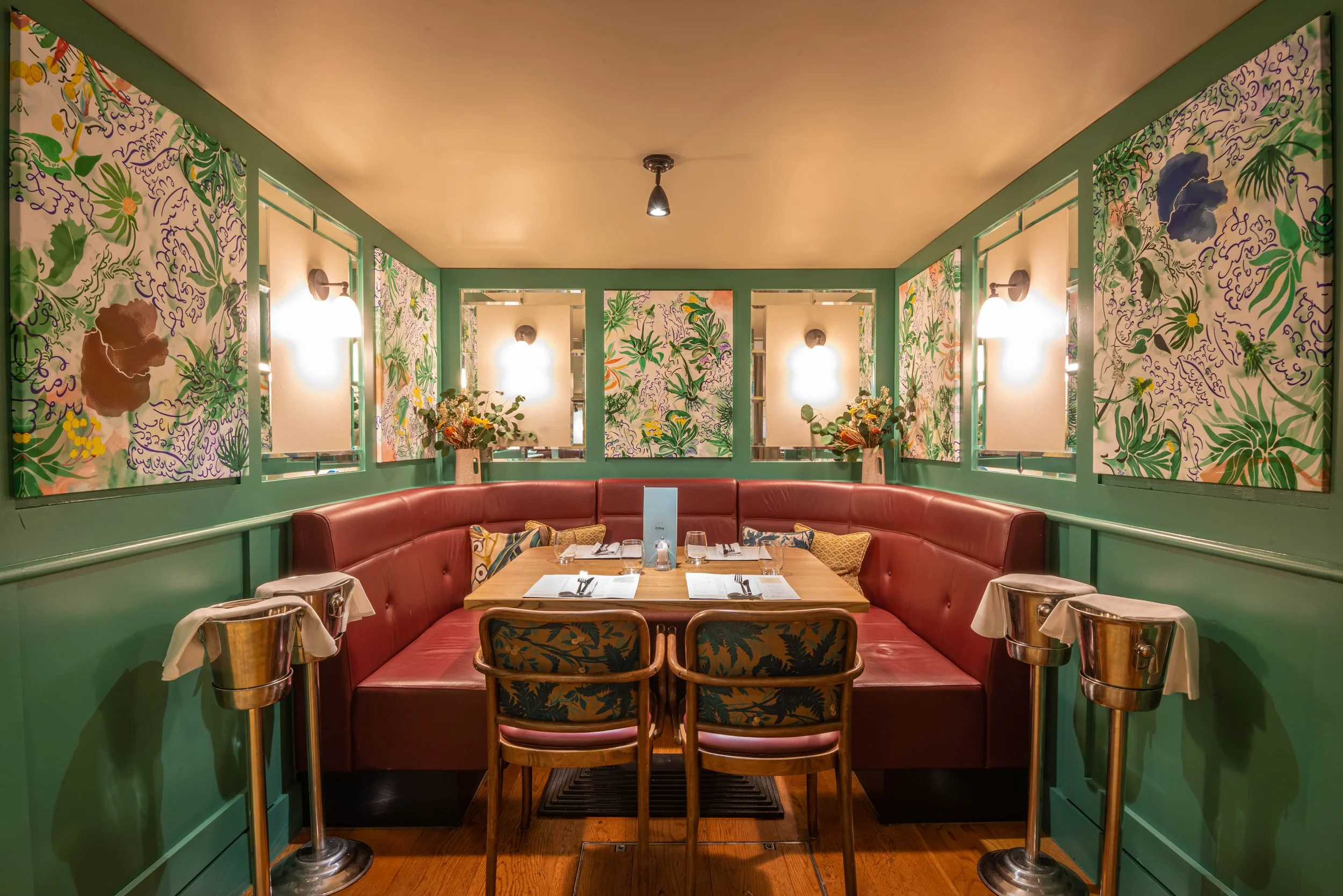 Cozy restaurant booth with red leather seating and green floral decor