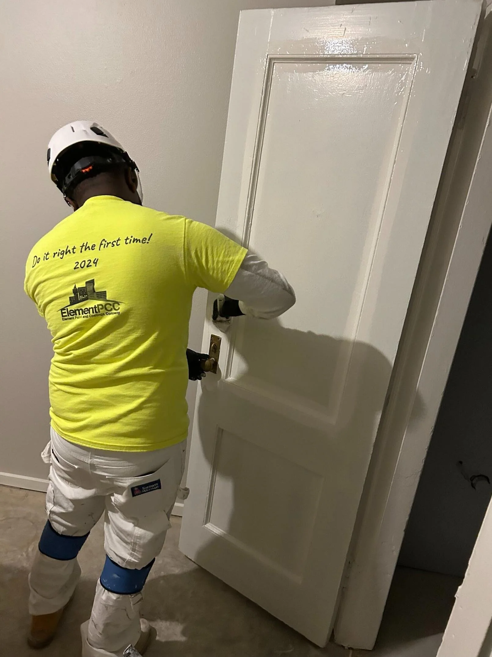 Bellevue painter painting interior doors at commercial office wearing element PCC uniform and safety gear