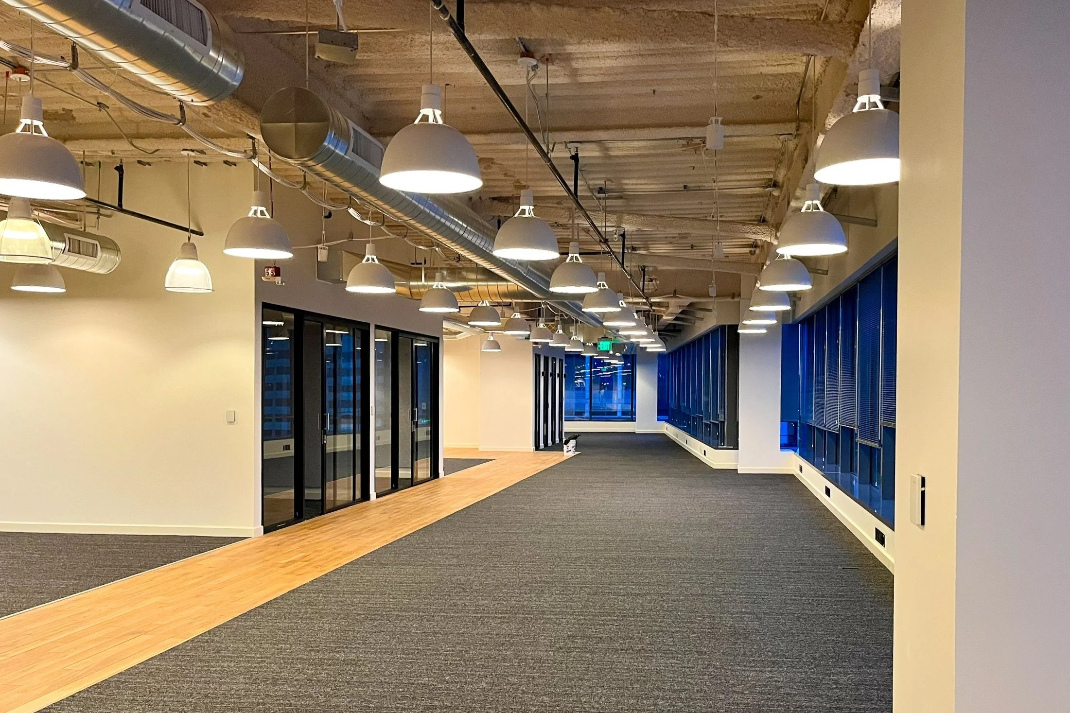 interior office building with beige paint grey carpet a wood hallway and big picture windows and black interior sliding glass office doors painted government office