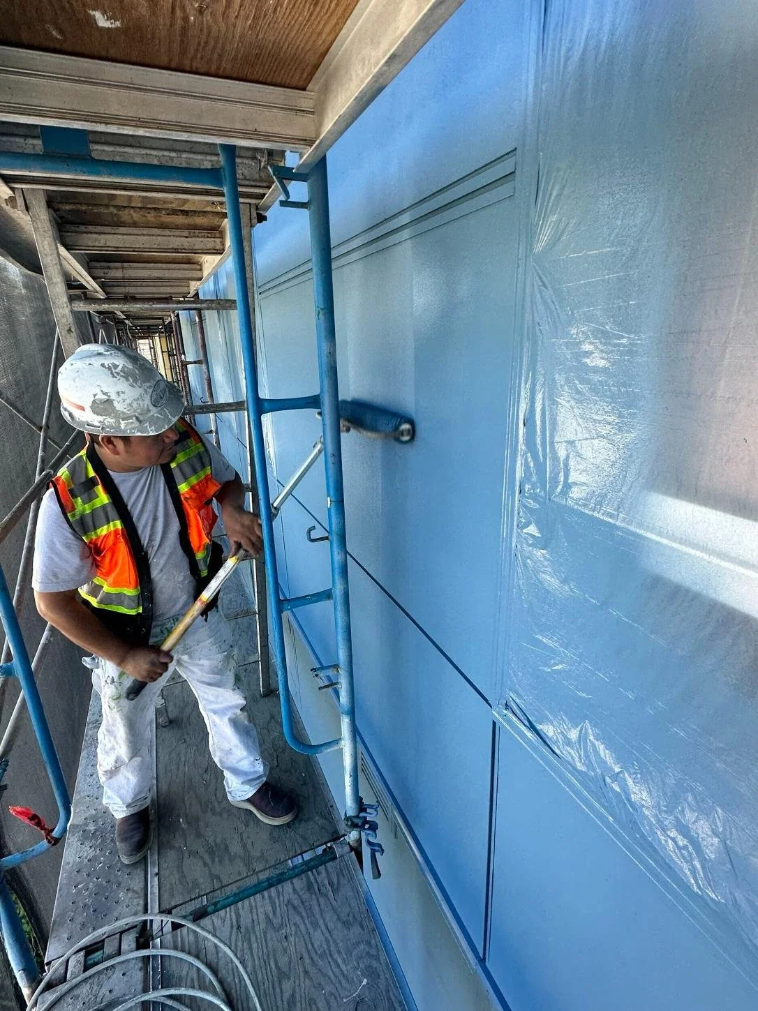 seattle painter on commercial apartment new construction rolling with 18" roller while on scaffolding sherwin williams super paint
