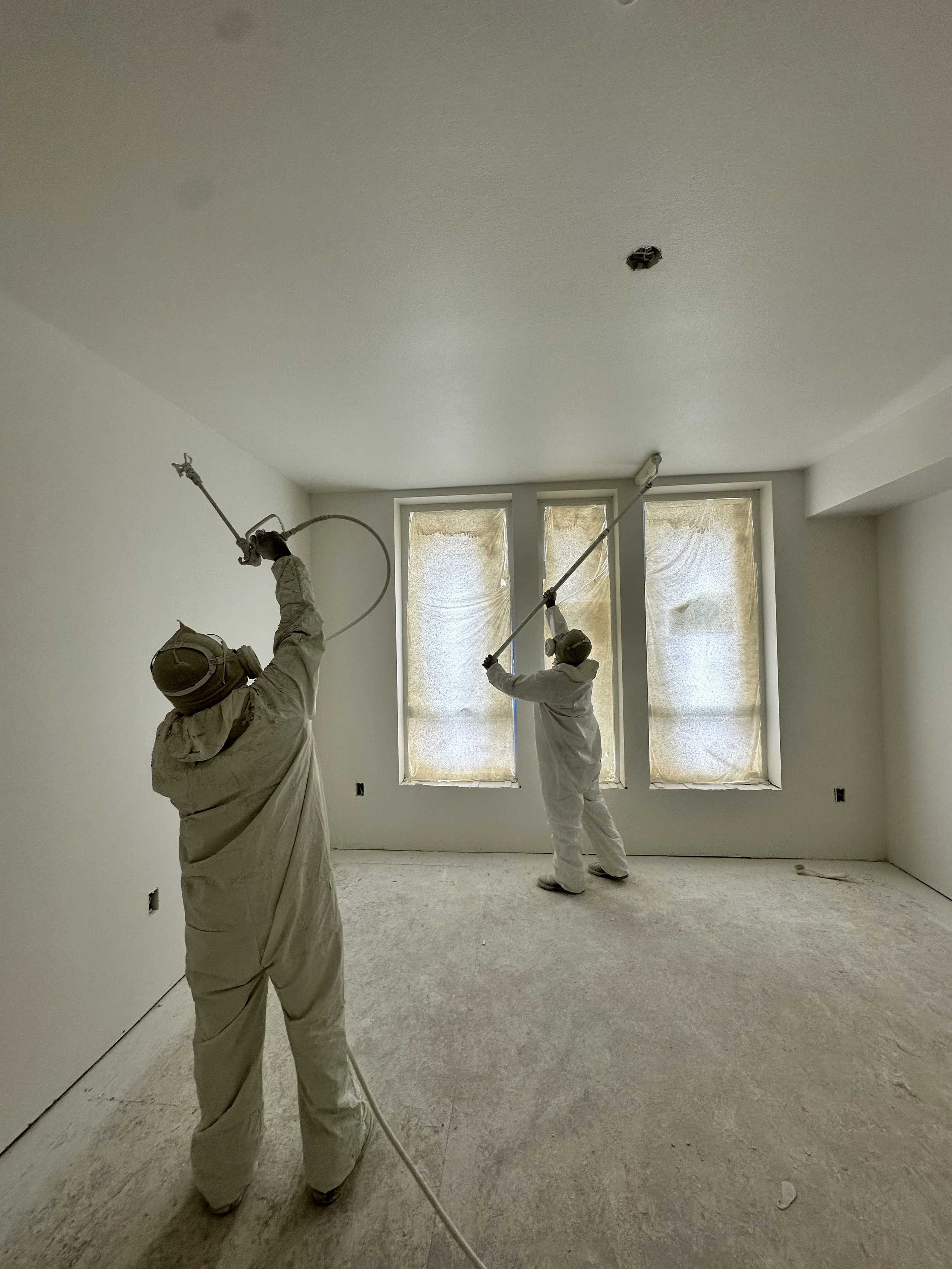 Commercial painters in Bellevue spraying paint on an interior space