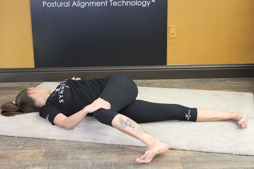 woman on the ground doing TFL Stretch (Bent Leg)