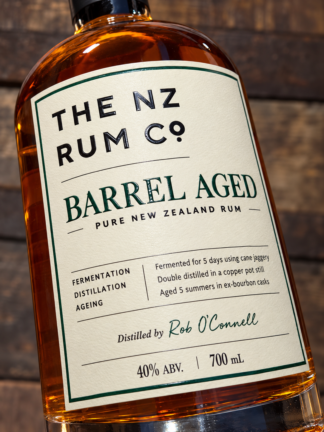 Close up of The NZ Rum Co Barrel Aged Rum bottle, showcasing its premium textured label, embossed lettering and rich amber New Zealand Rum.