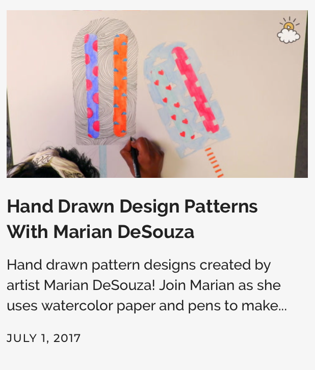 A person using a black marker to draw on a watercolor paper ice cream cone with a striped design, held upright on a white background.