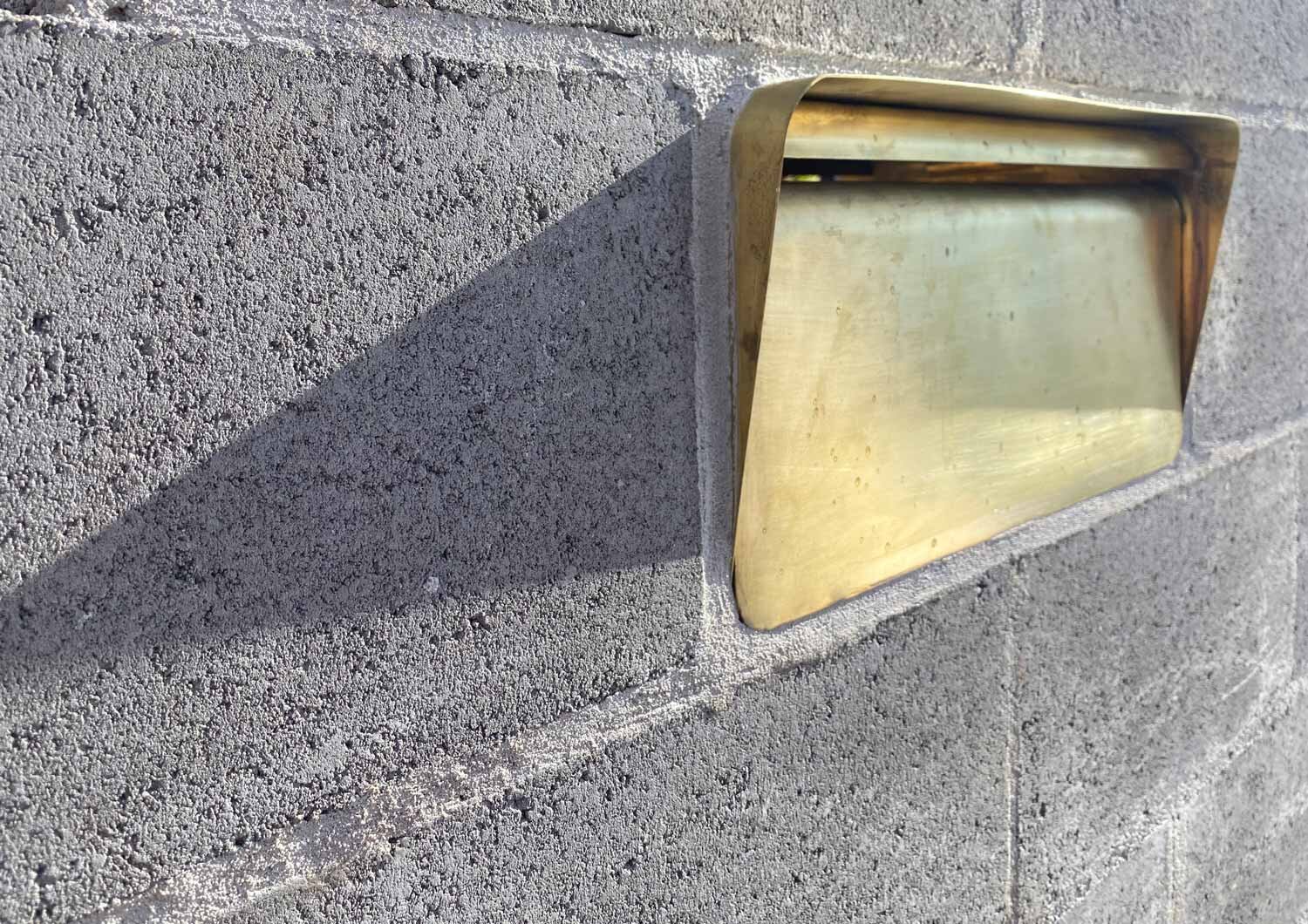 Brass in-wall letterbox | Besser by Hatchet Studio Sydney | angled front view brass in-wall letterbox installed in concrete block wall.
