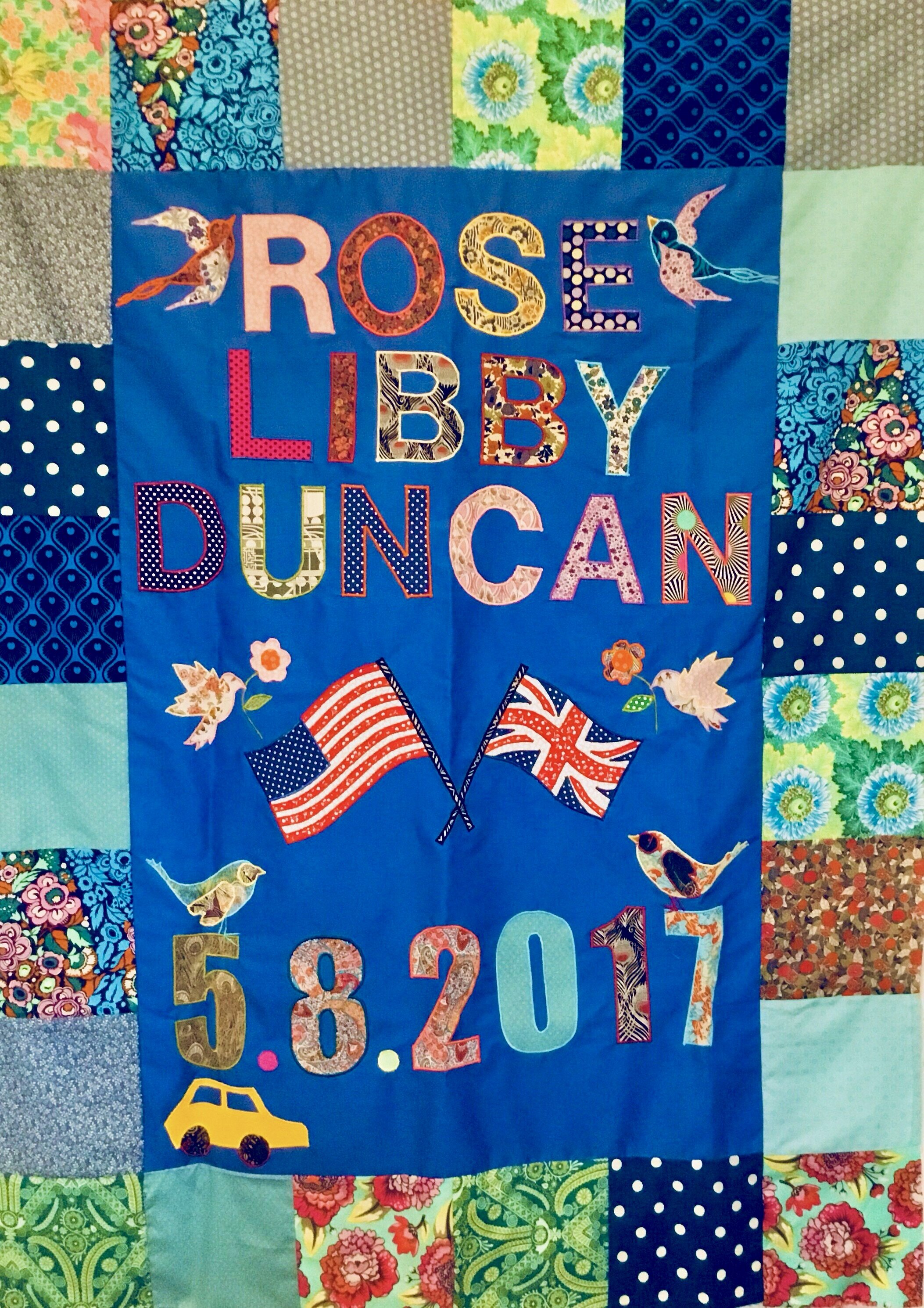 This personalised birth quilt celebrates the birth of the couples daughter and their USA and UK connection. Their love of birds and an old car once owned also feature.
