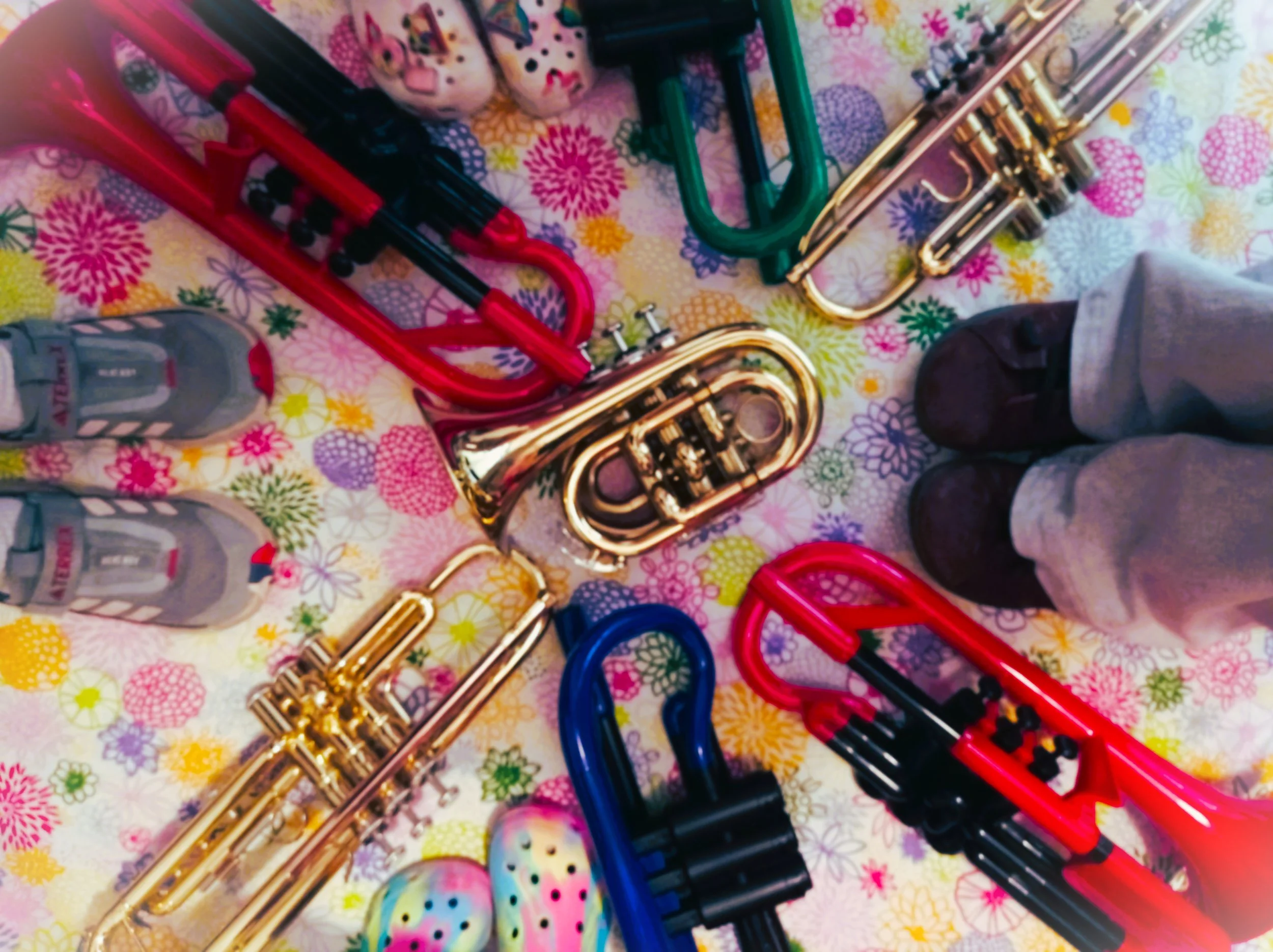 Colourful metal and plastic trumpets in a circle, along with shoes.
