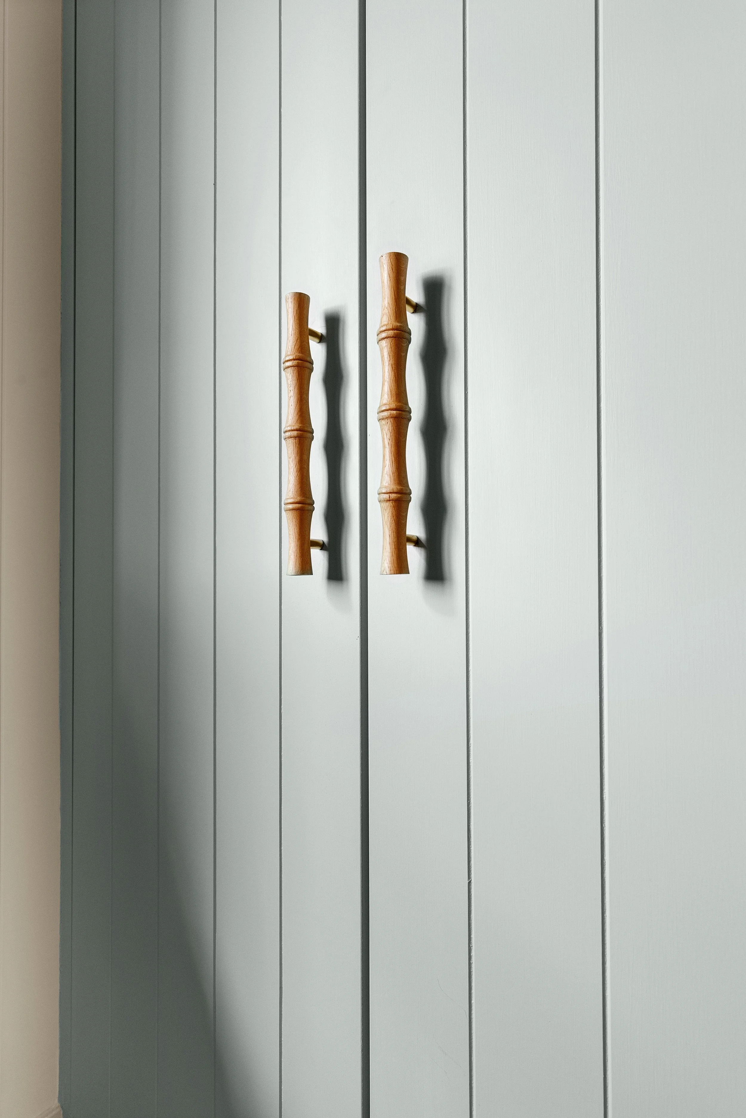 Light blue wooden closet doors with bamboo-style handles.