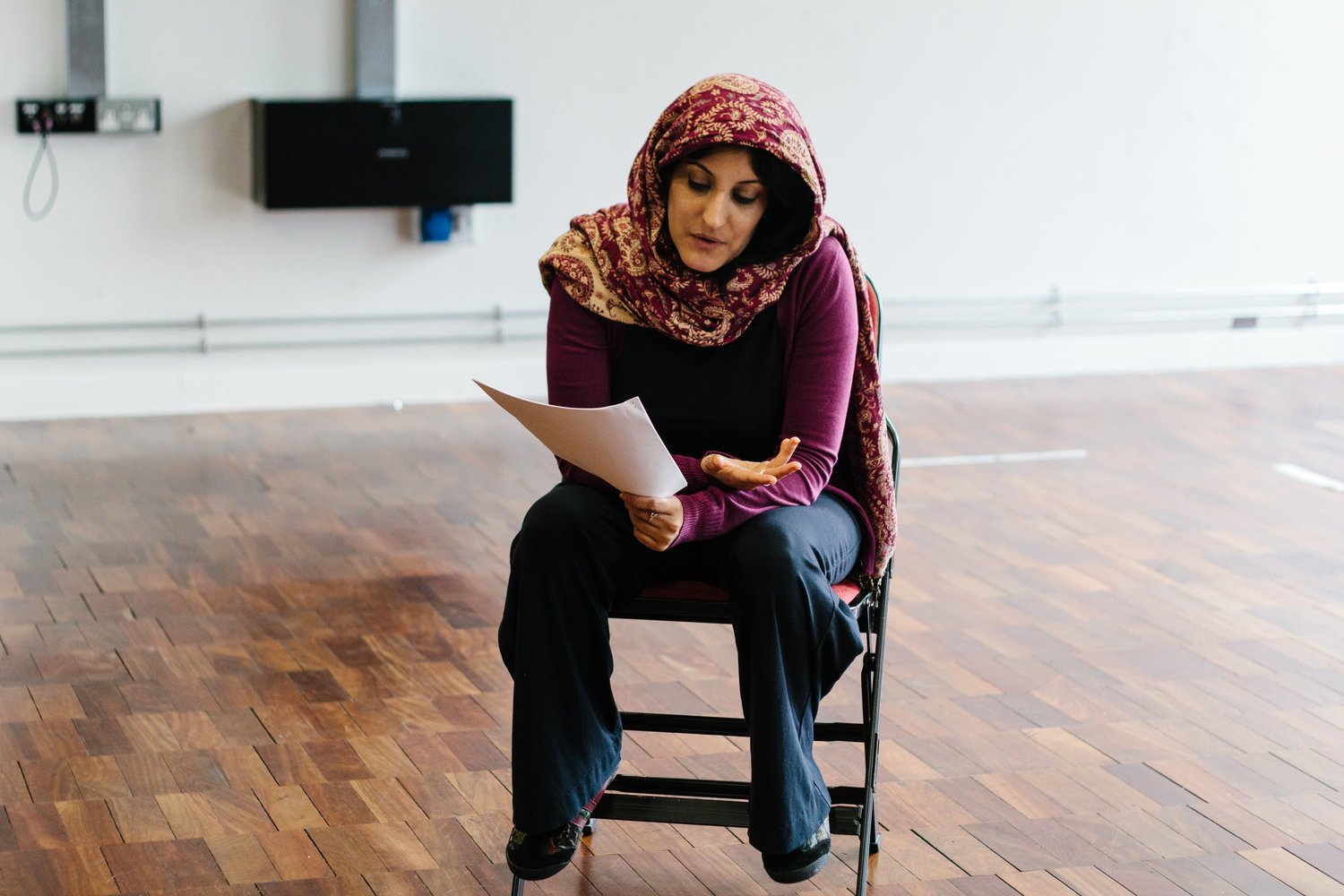 photo of Renu Arora sitting on a chair reading the script From Running Water