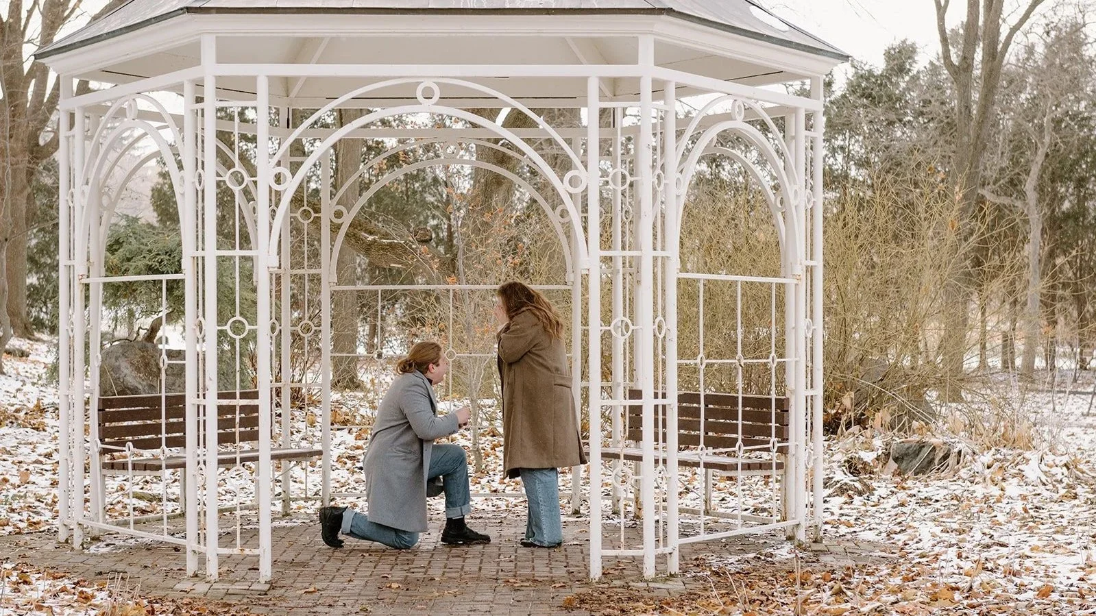 proposal under a white gazebo with light snow on the ground