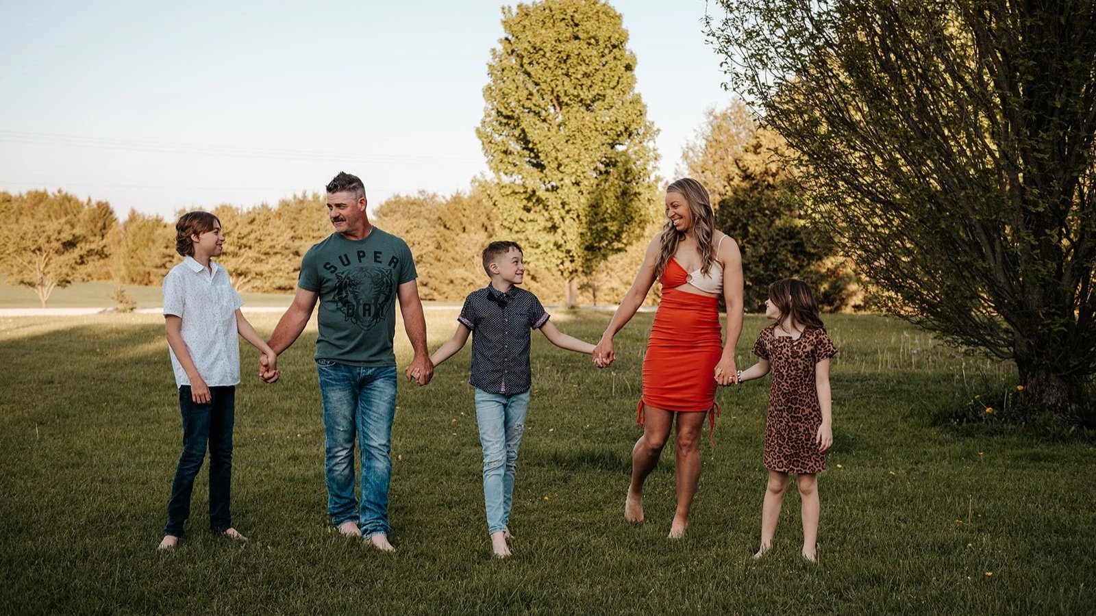 family holding hands and walking on their lawn