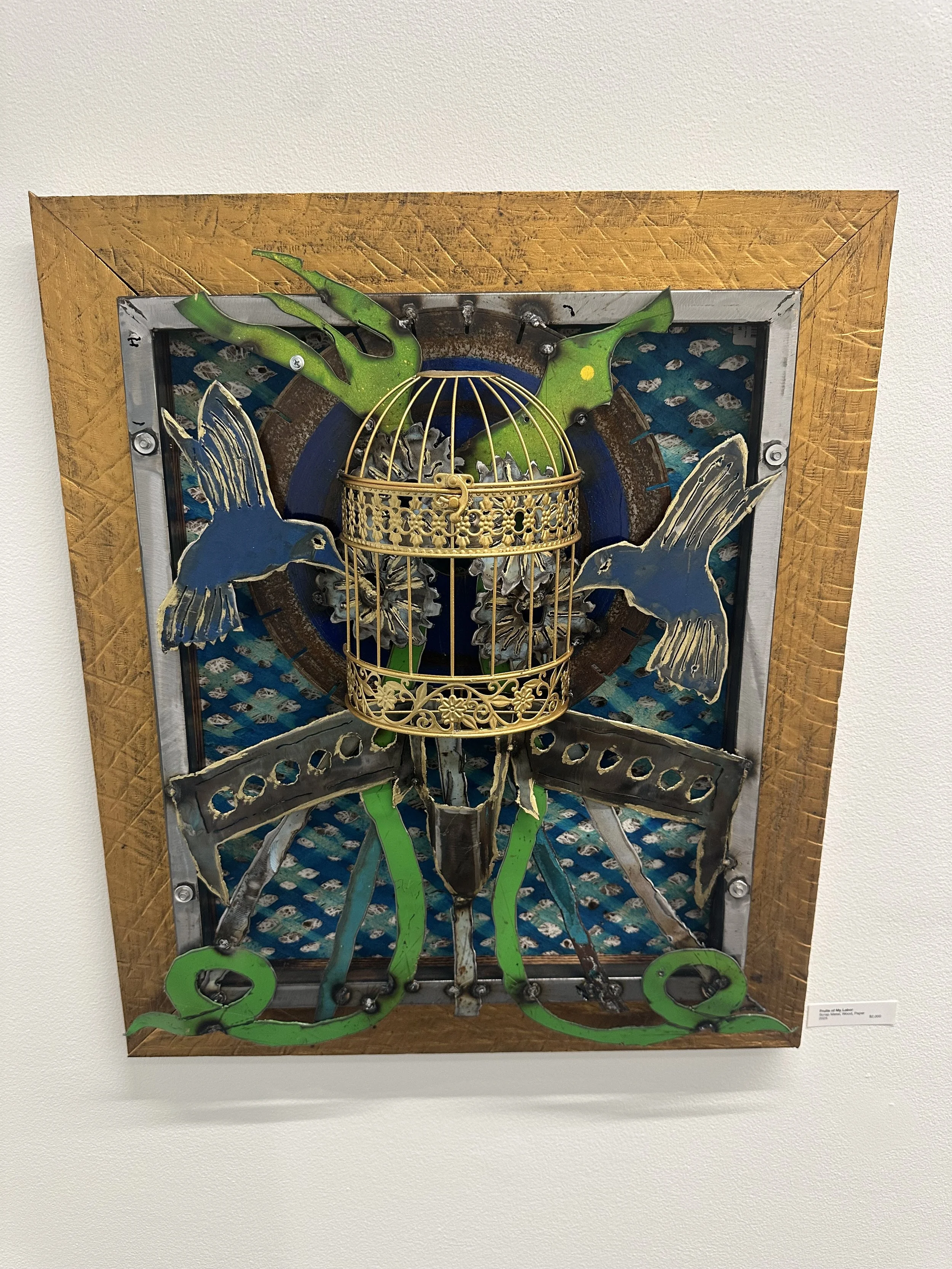 Mixed media art piece featuring hummingbirds and a birdcage with green and blue accents mounted on a wooden frame.