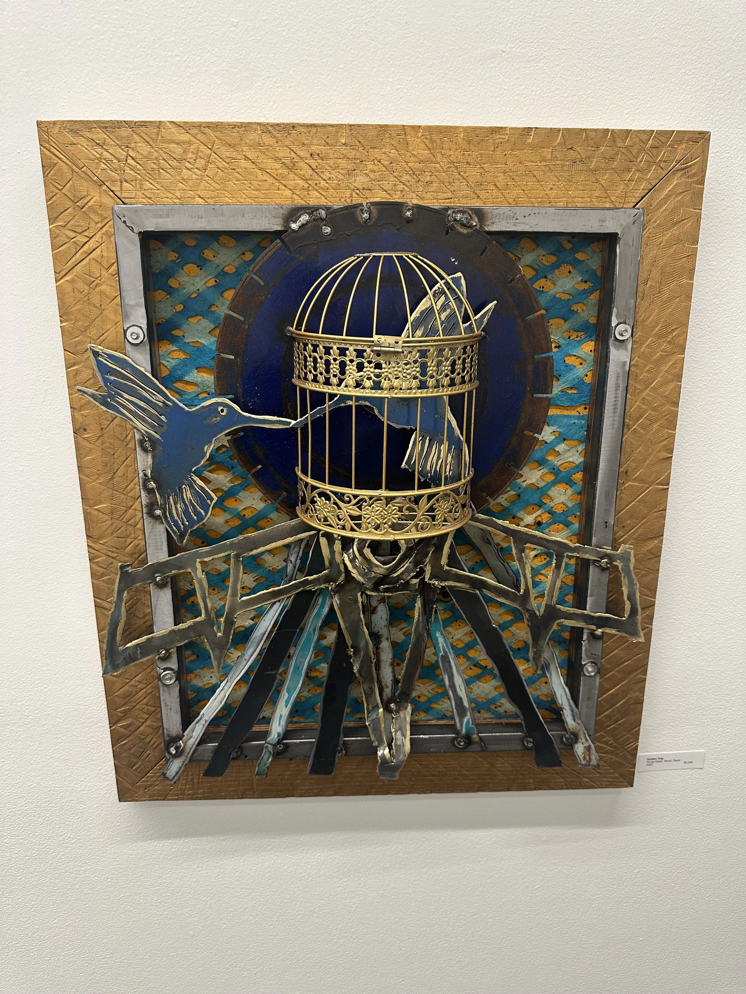 Mixed media artwork featuring a blue and gold bird in flight, a gold birdcage, and geometric shapes on a textured background with a wooden frame.