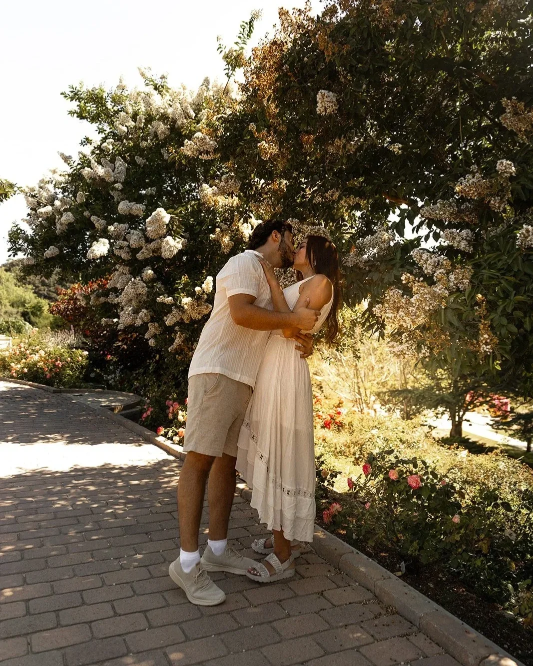 Couple standing back to back surrounded by flowers at South Coast Botanic Garden, a scenic Los Angeles proposal location