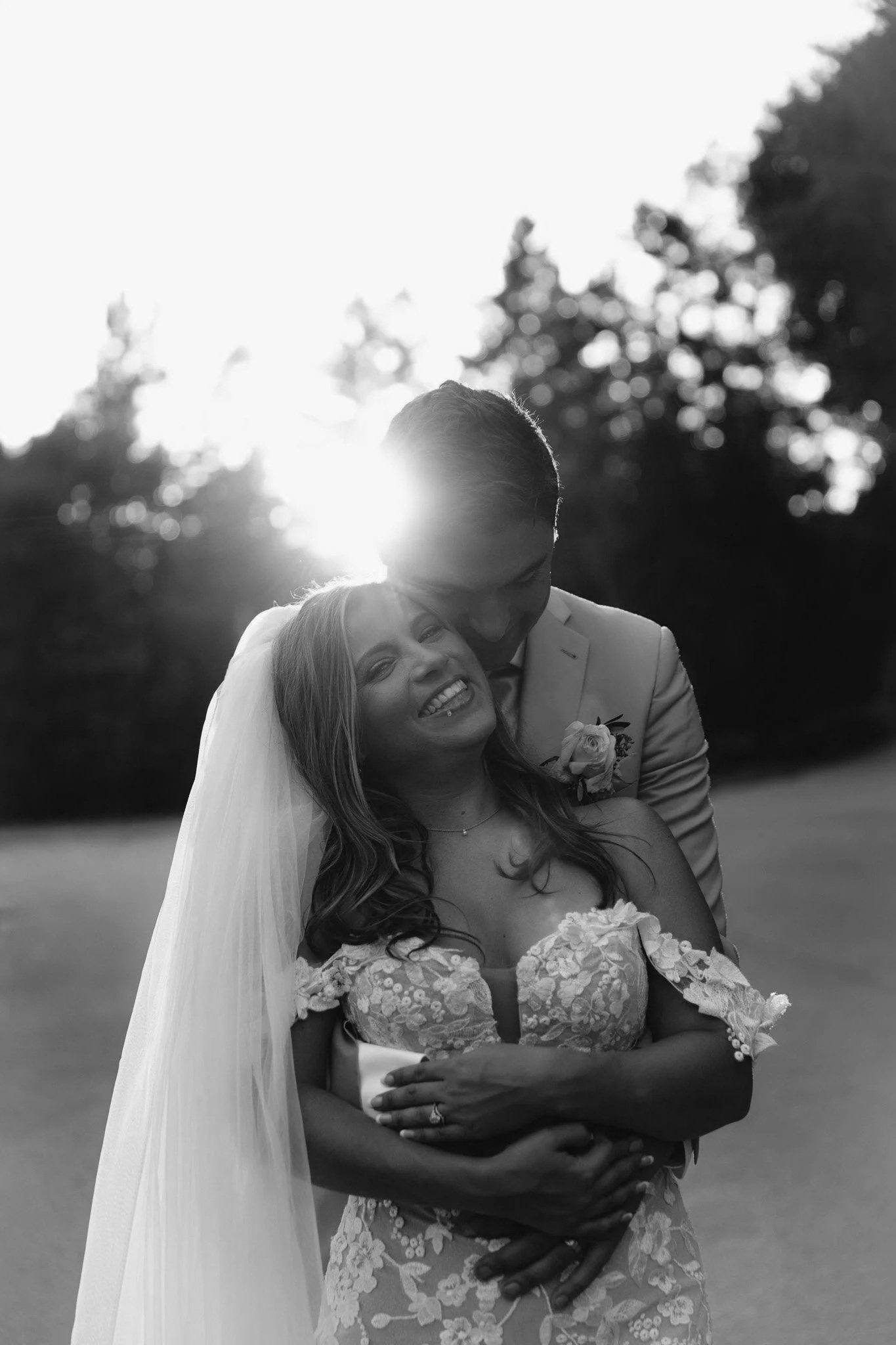 A bride and groom embrace and smile outdoors at sunset, beautifully captured by a Midwest Wedding Photographer.