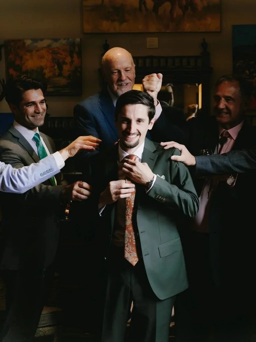 Group of men in suits celebrating together at a social gathering, smiling and joking.