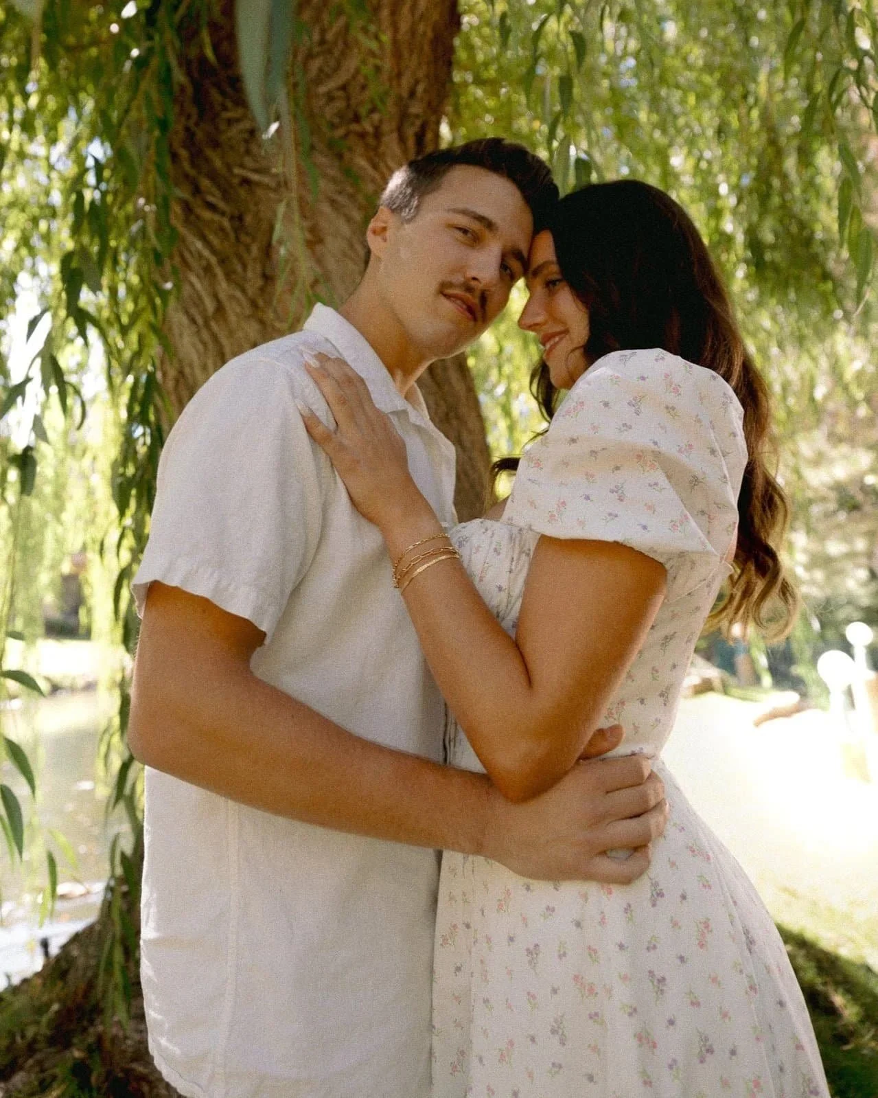 Natalie and Tom embracing under willow trees at La Caille in Holladay Utah during a romantic proposal session
