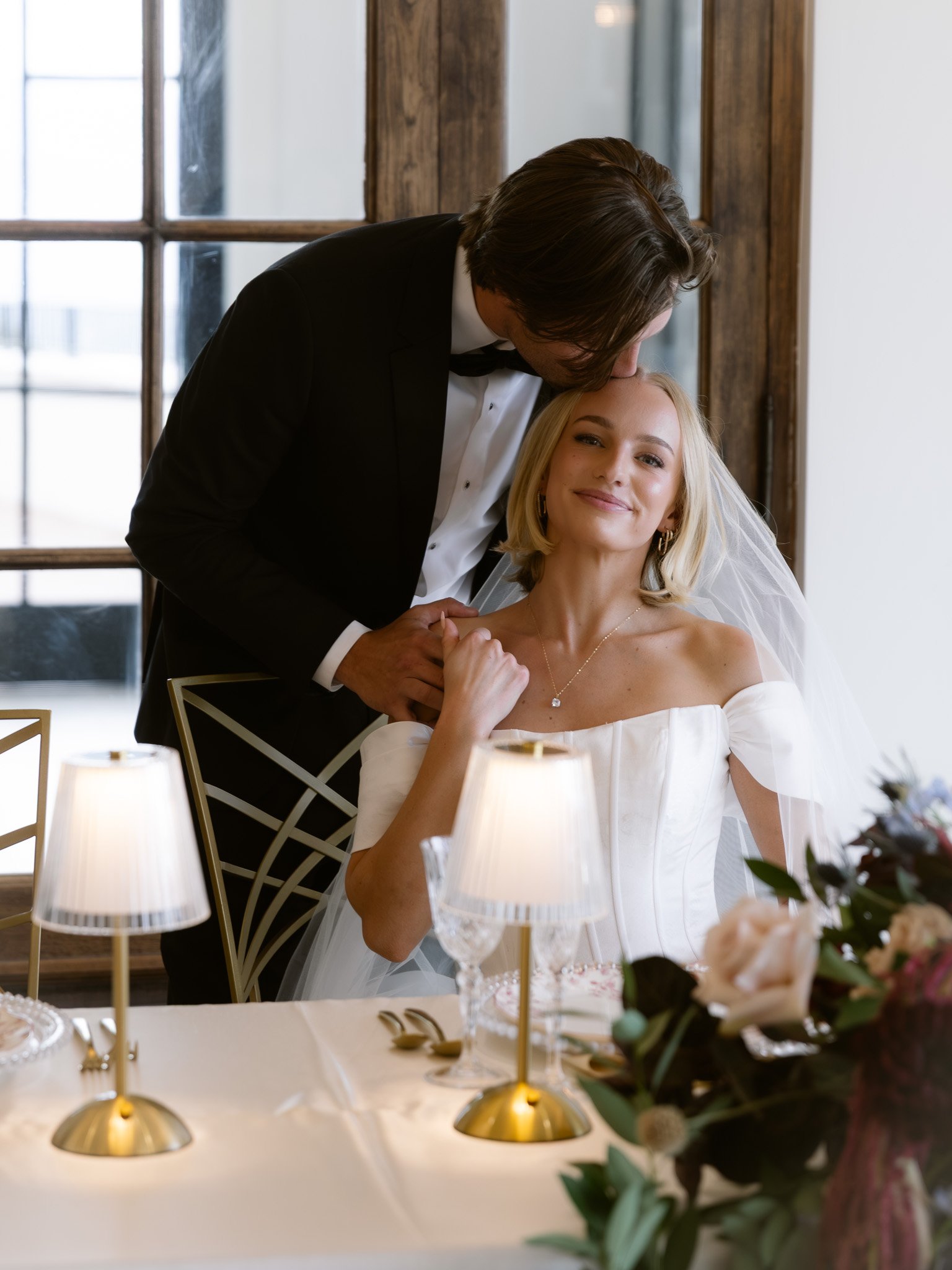 Siempre Utah Groom kissing bride on forehead at sweetheart table | by Jenna Roden