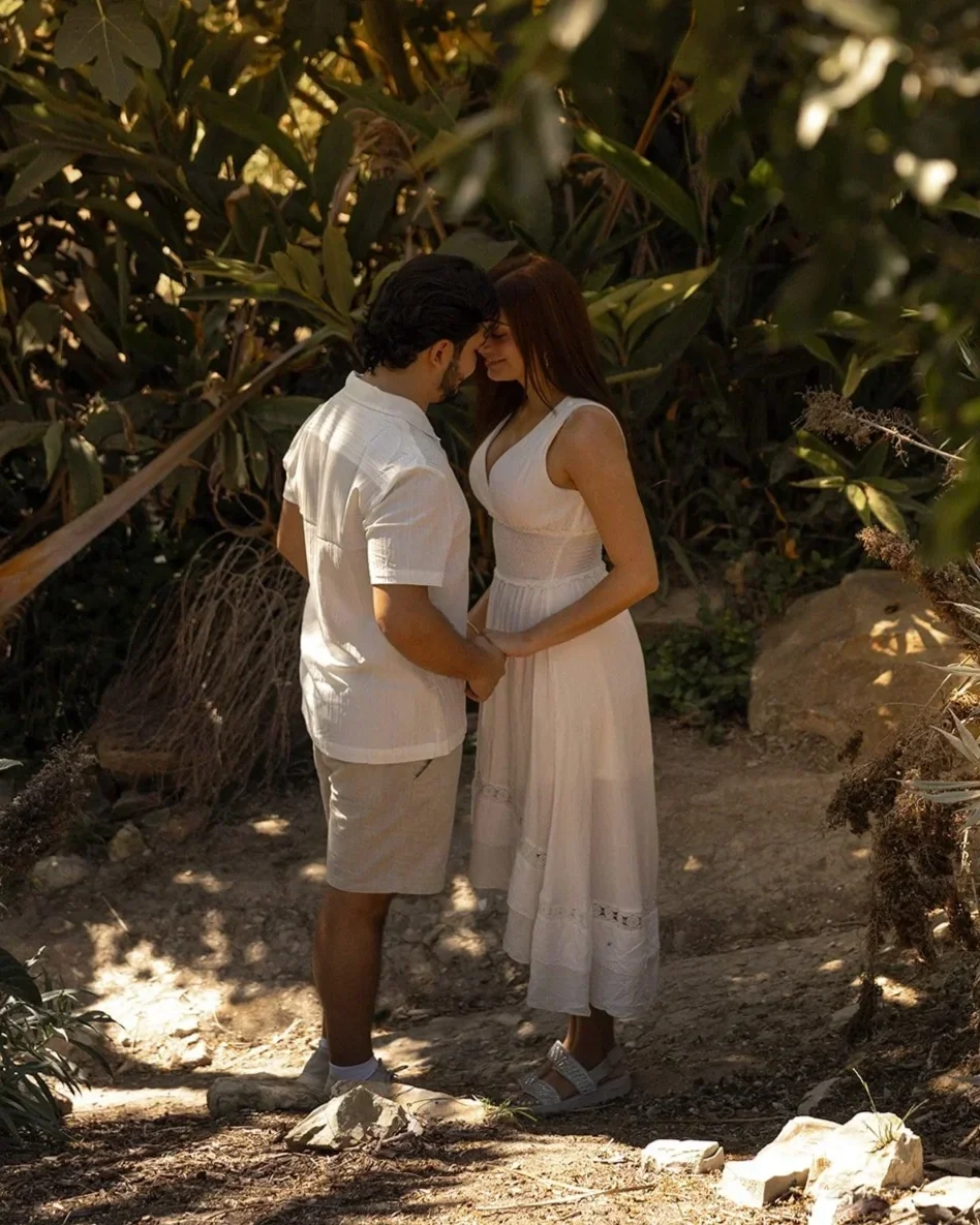 Couple sitting together under greenery at South Coast Botanic Garden in Los Angeles during an intimate proposal session