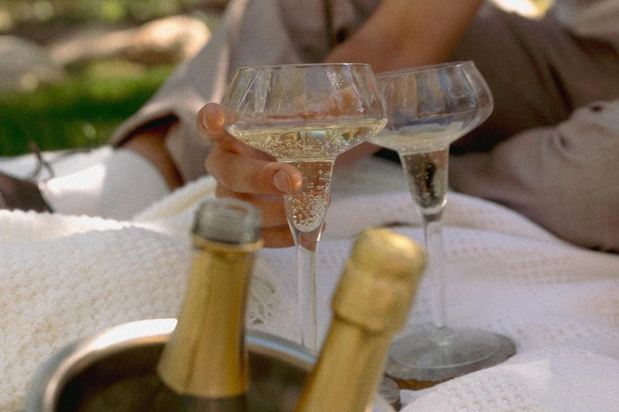 Champagne toast during La Caille proposal picnic with soft editorial styling and intimate details