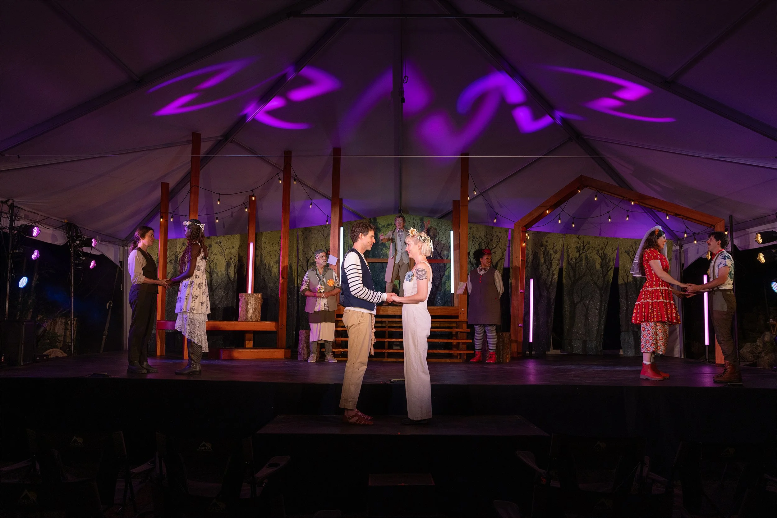 a young couple stand together among their friends on stage
