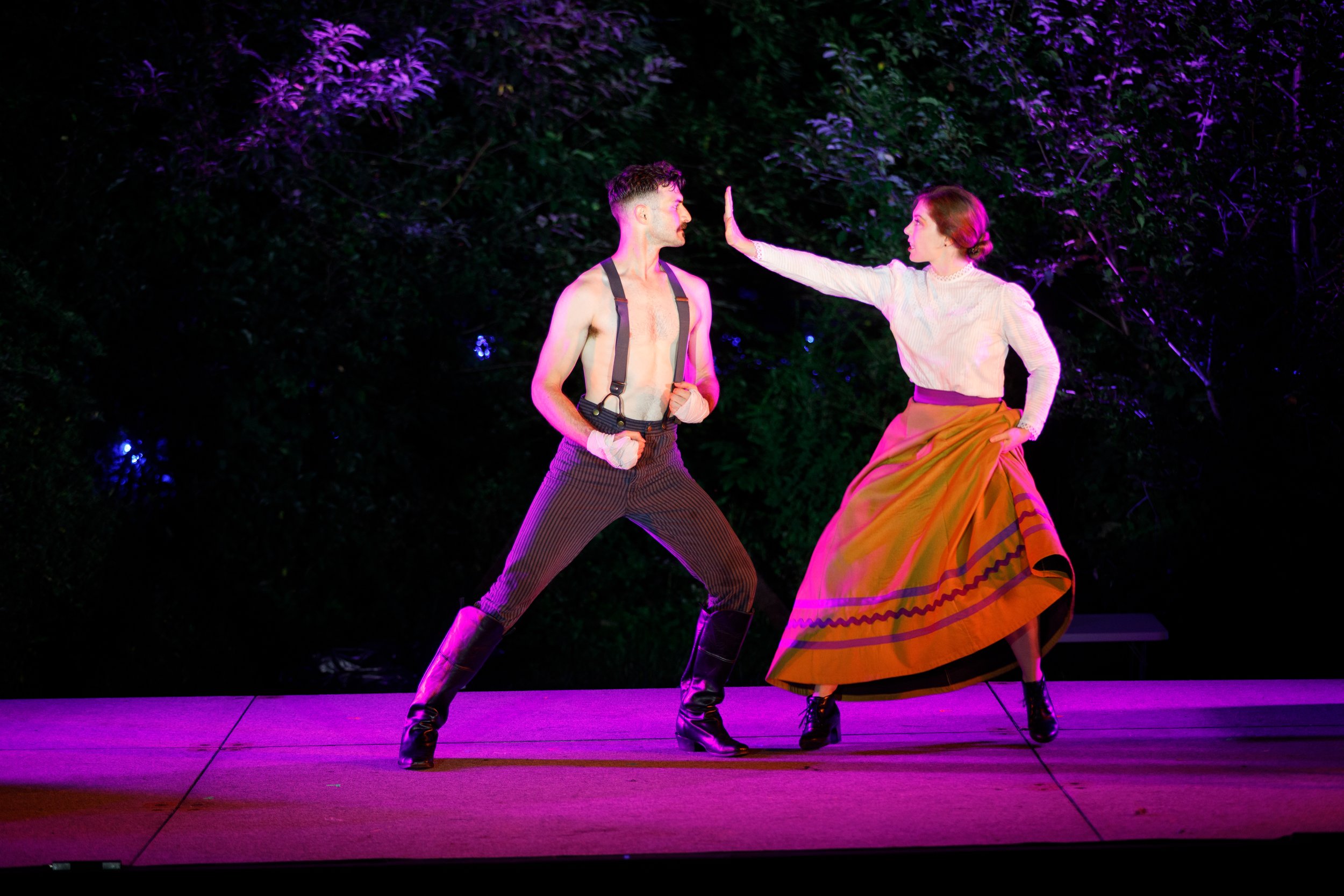 woman holding hand up to man in boxing stance's face on stage