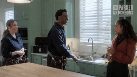 Plumbers in a kitchen motioning to the sink doing a ta-daaa motion to their client. The image supports this articles analogy about brands needing regular maintenance so they don't 'burst' like a hot water cylinder.