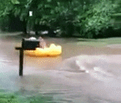 Personl floating down a flooded street in a giant blow up duck
