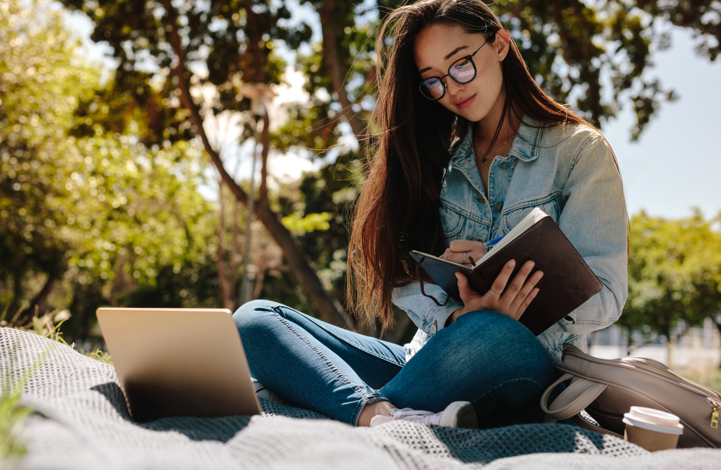 Woman with ADHD attending therapy via telehealth while sitting on a blanket outdoors.