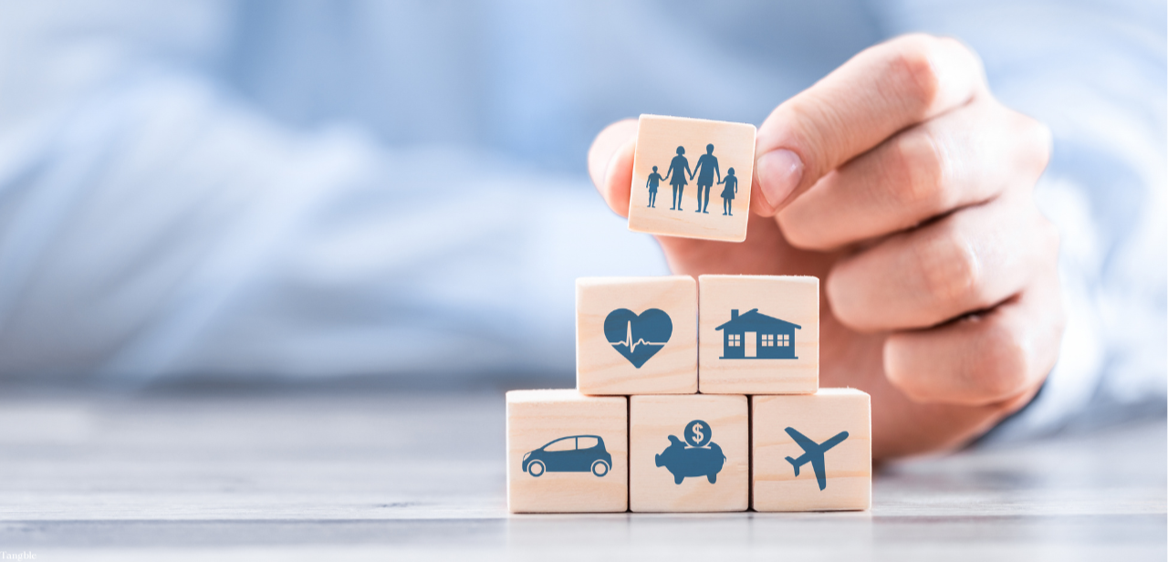 A hand stacking blocks with images on them that show what is covered by insurance such as Tangible Therapy