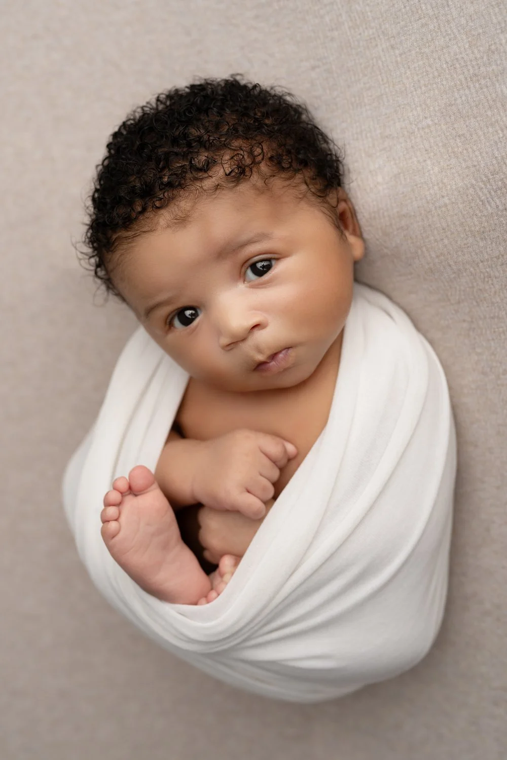 Newborn baby boy with eyes open wrapped up for columbus ohio newborn photography session