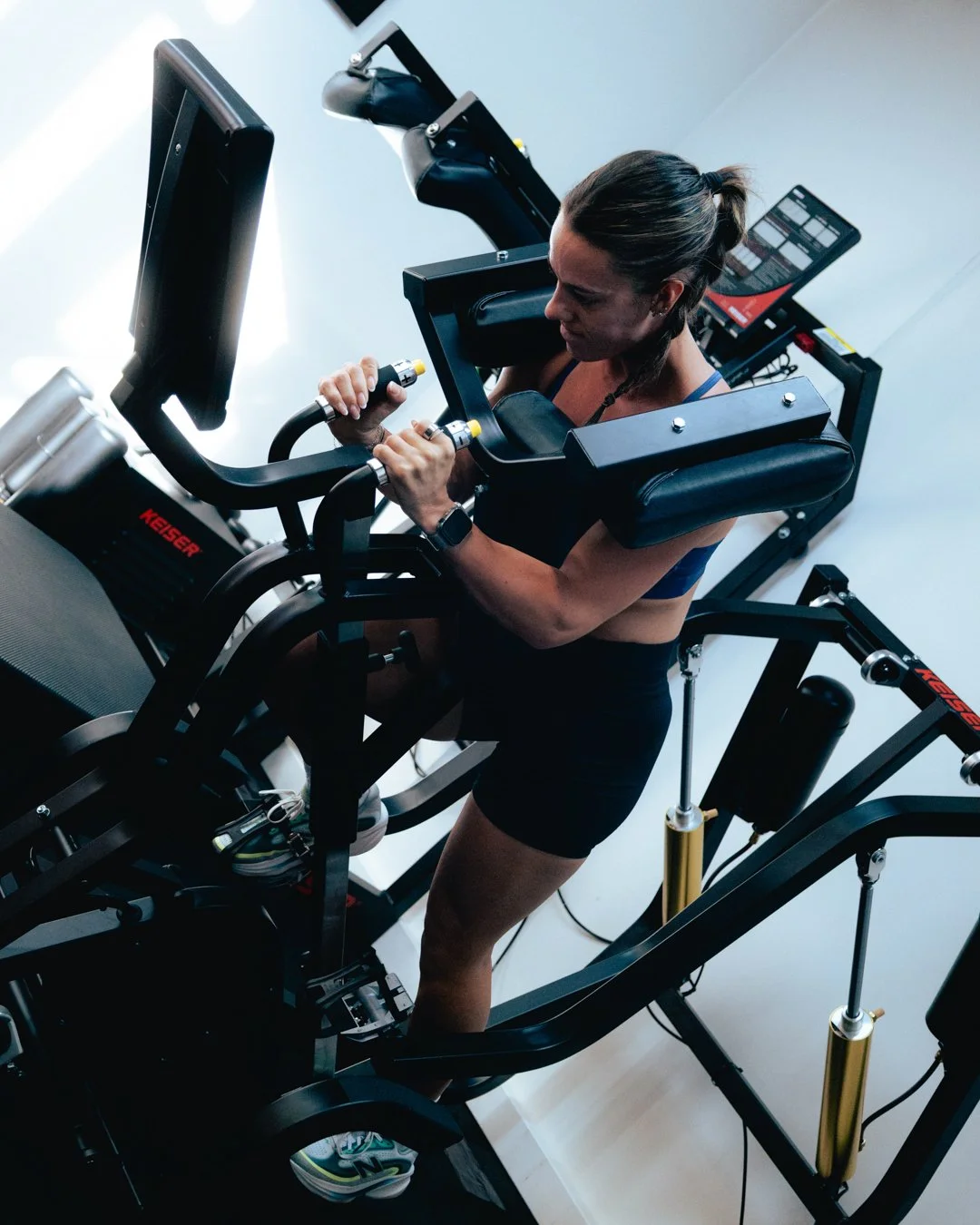 A woman exercising on a treadmill with a support harness at the gym.