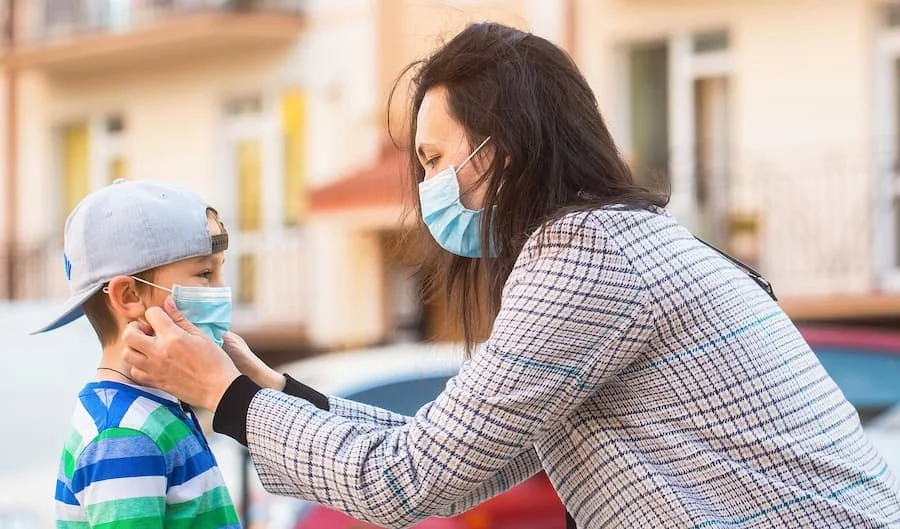 a woman putting a mask on a child