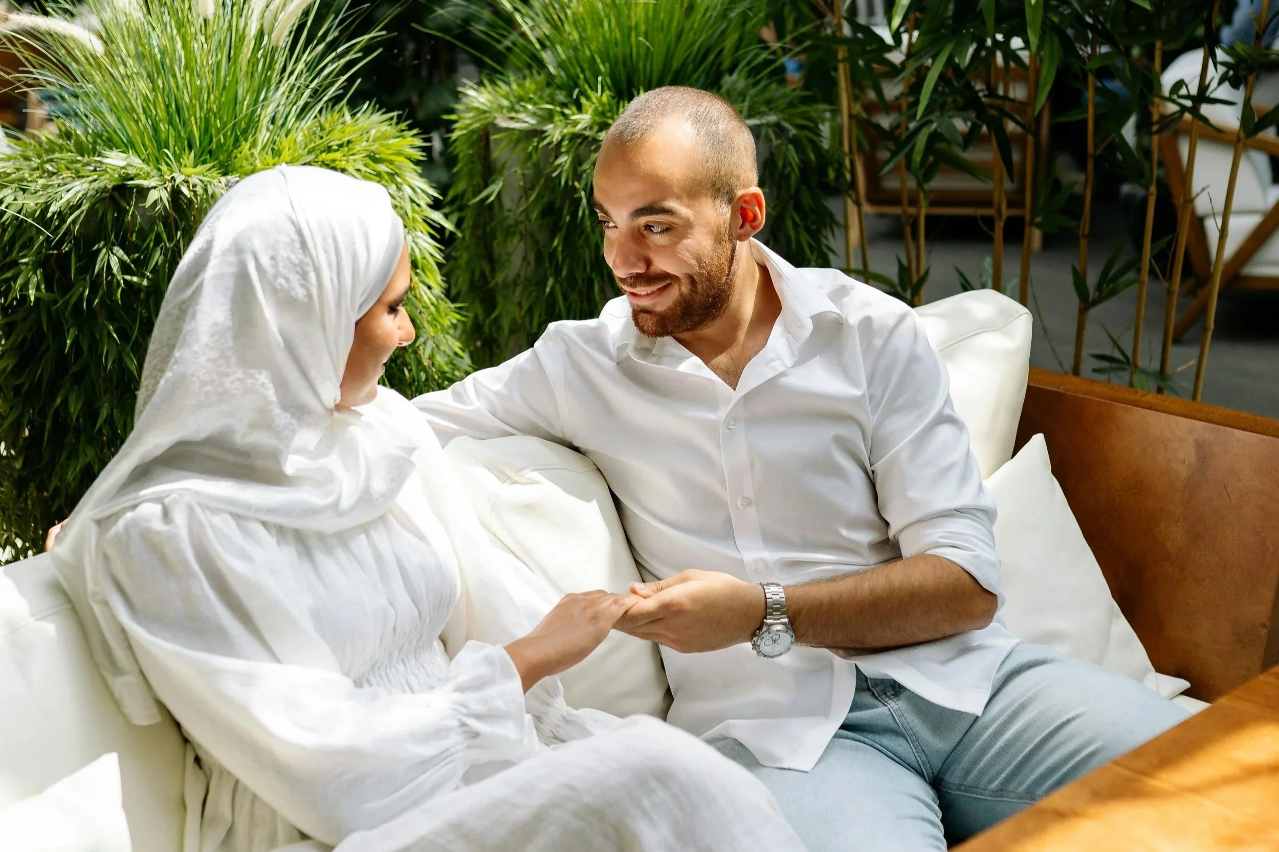 A couple holding hands on a couch, symbolizing support and connection while navigating the impact of past trauma in their relationship.