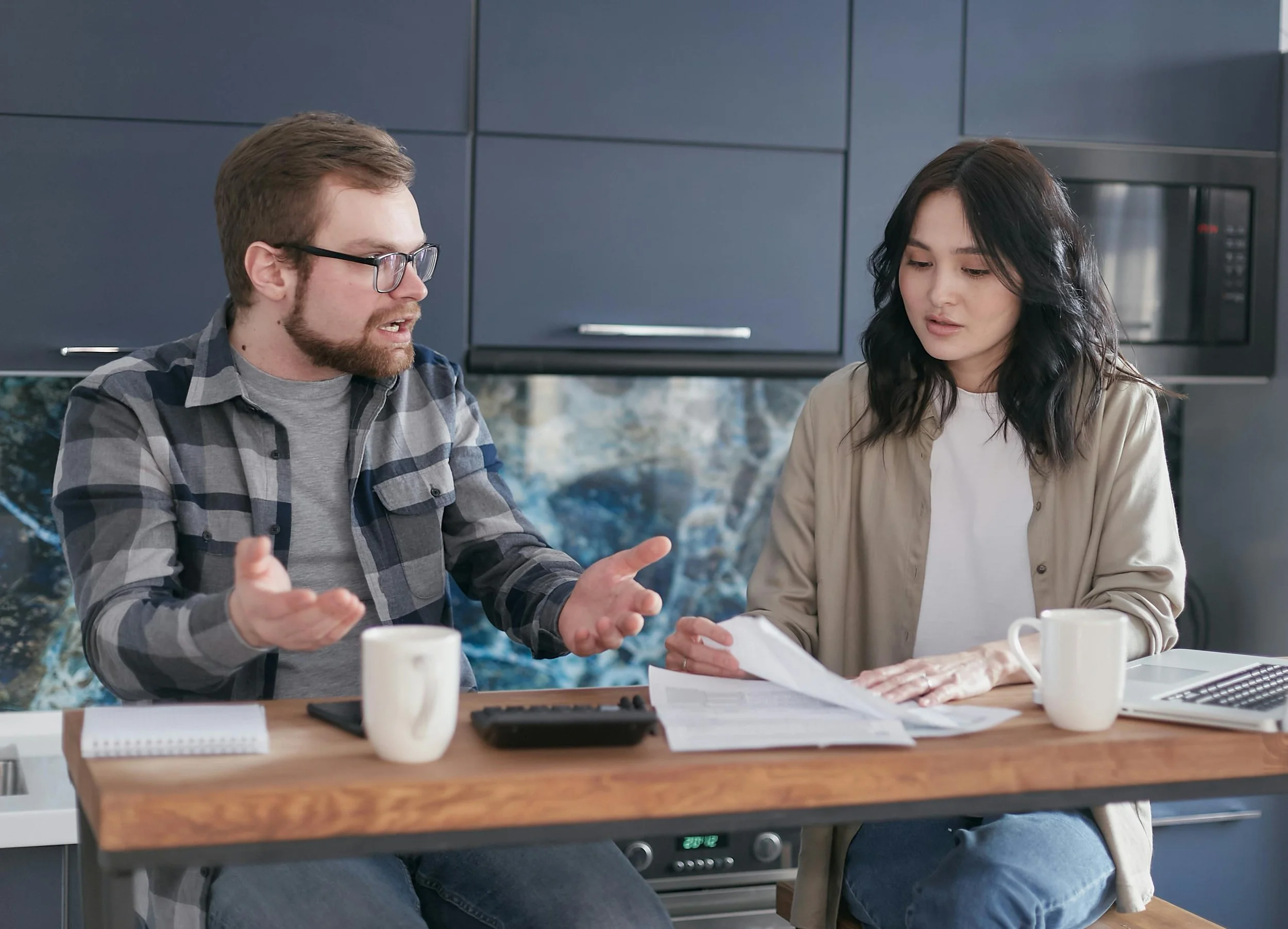 A couple discussing a family schedule at a kitchen table, symbolizing communication and shared decision-making in blended families and co-parenting.