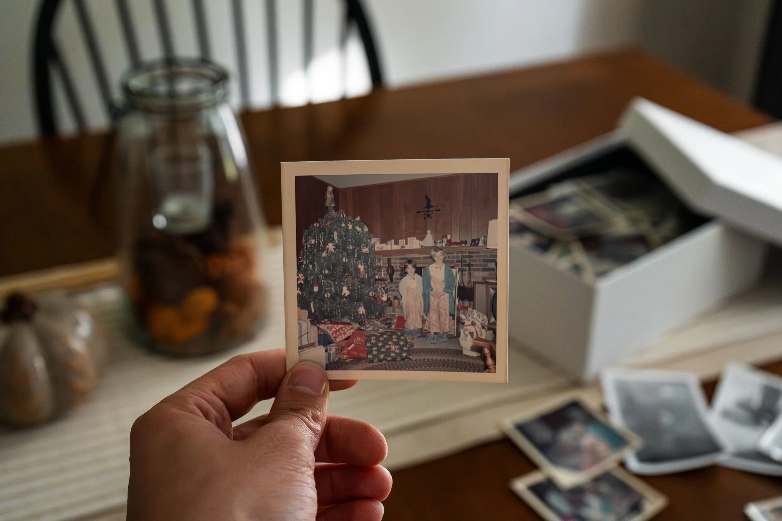 Adult looking through old photographs while reflecting on a meaningful period of life