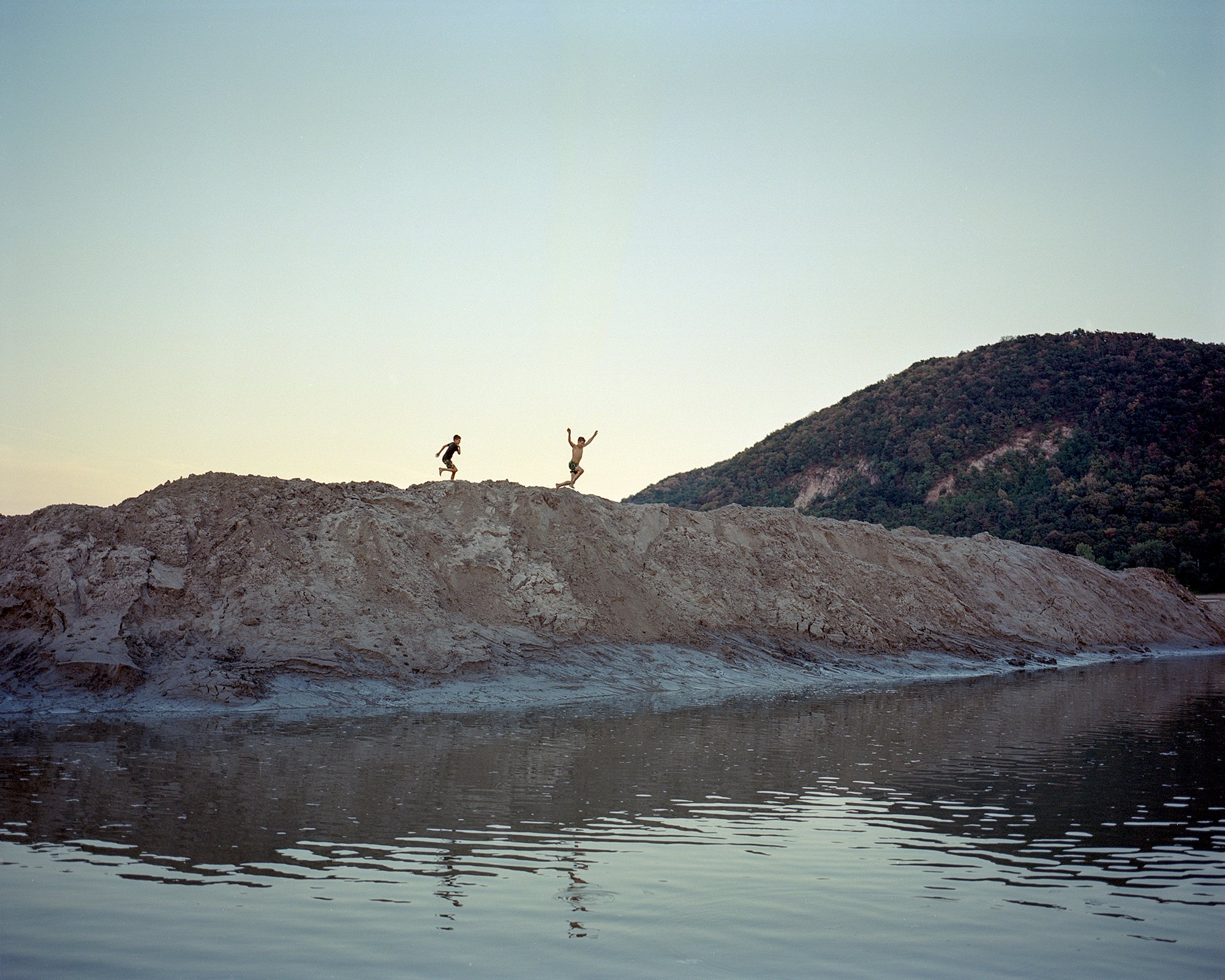  Children jumping from a riverbed dredge at Danube. Nagymaros, Hungary, 2022 