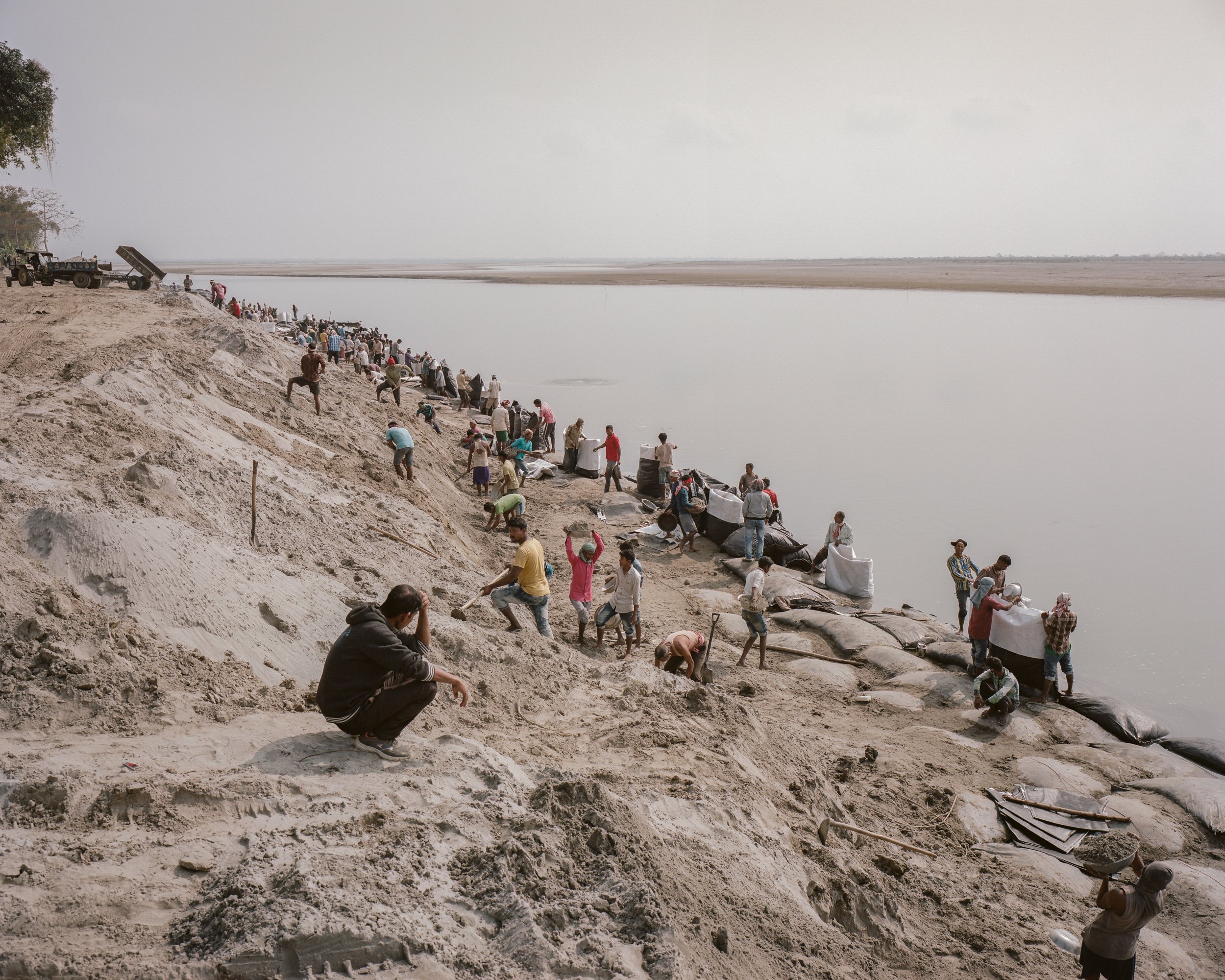   Villagers collect sand from the riverbed of Brahmaputra, and transport to endangered part of the riverside in order to build sandbag embankments.    Kumar Gaon, Majuli, India — 2020  