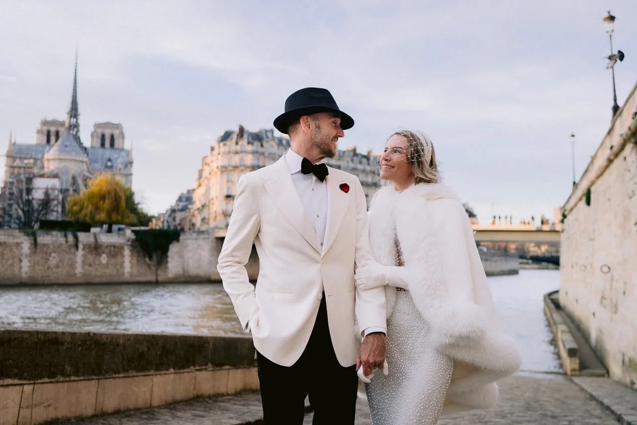 Couple walking hand in hand in Paris after their wedding, photographed near classic Haussmann architecture