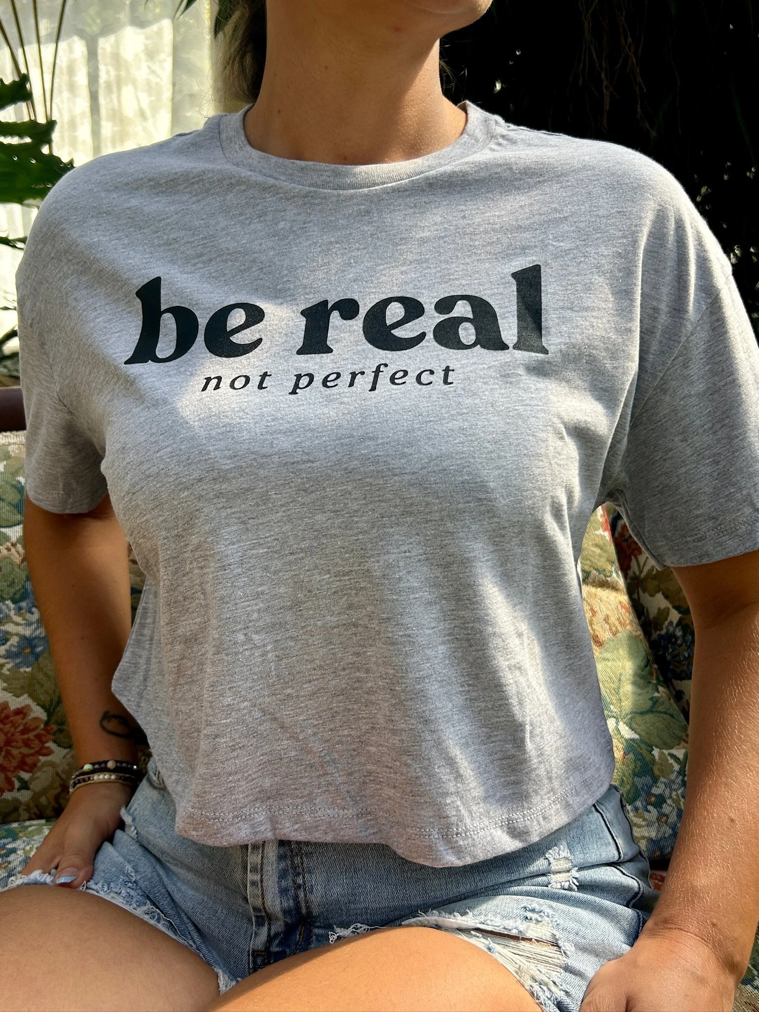 close up view of a gray t shirt saying be real not perfect