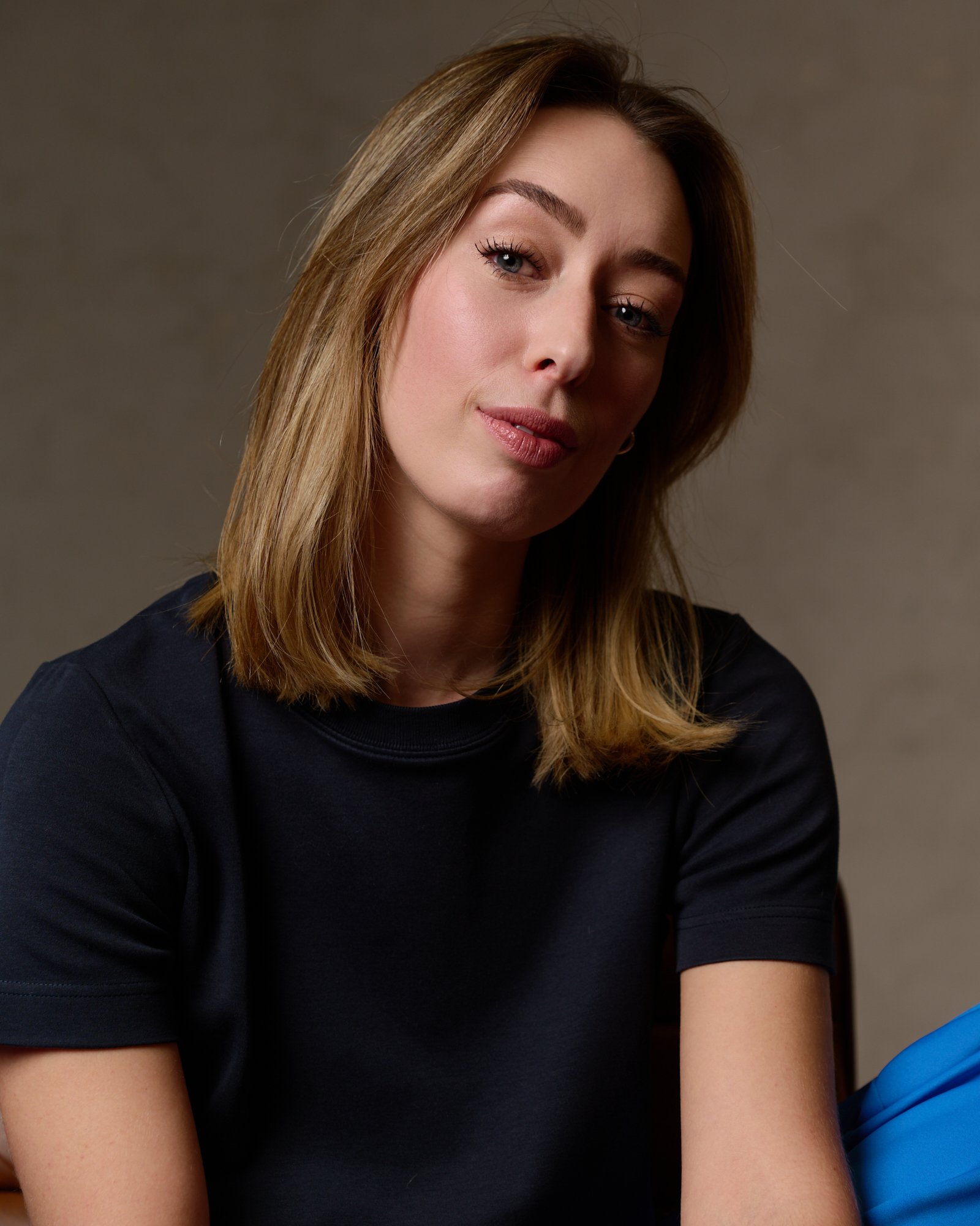 A woman with light brown hair, wearing a black shirt and blue gloves, engaging in a medical or dental procedure.