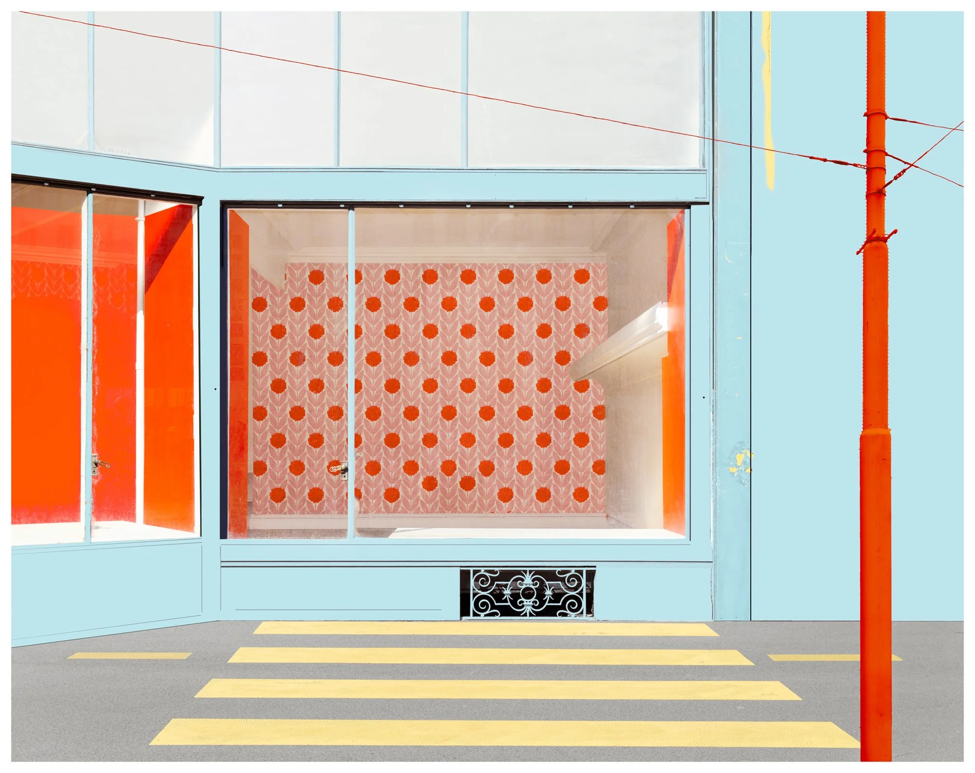 A storefront with large windows, decorated with orange and pink floral wallpaper. The entrance has glass doors with orange panels on either side. There is an orange drainpipe on the right, and yellow and gray pavement in front.